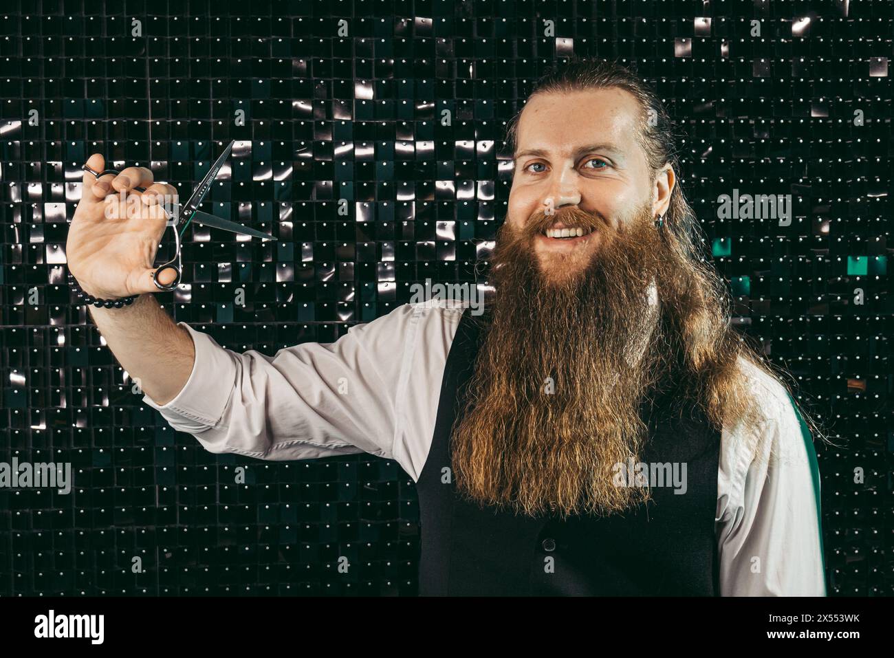 Portrait de barbier barbu avec des ciseaux. Homme jeune barbier coiffeur professionnel avec une longue barbe et les cheveux en gilet avec des ciseaux dans les mains portrait, coupé Banque D'Images