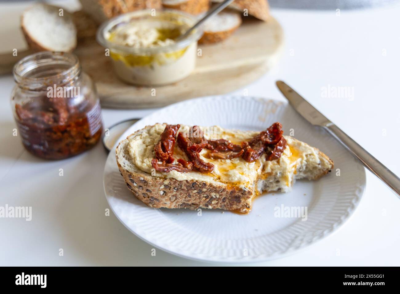 Morceau de pain avec houmous sur une assiette blanche Banque D'Images