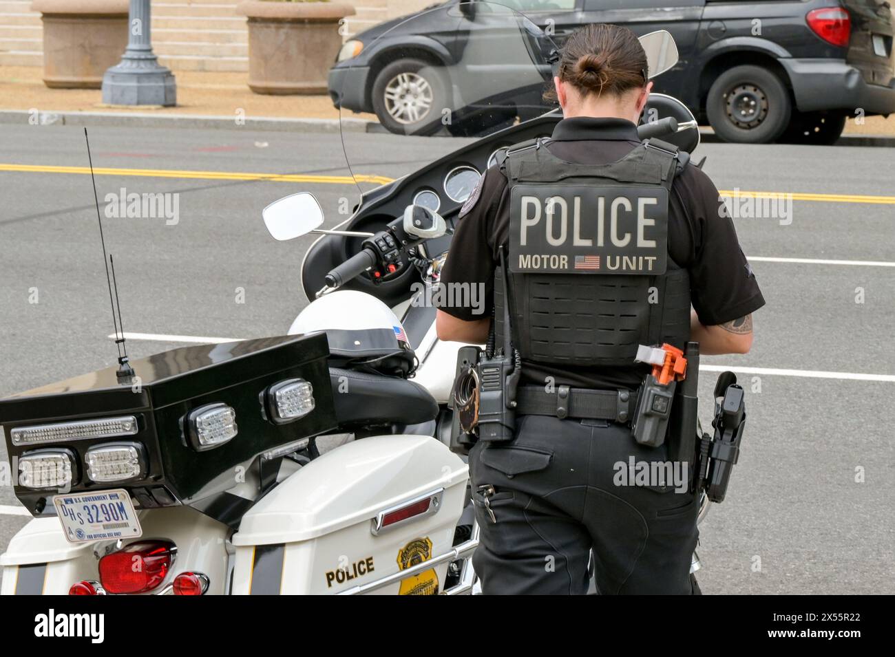 Washington DC, États-Unis - 1er mai 2024 : officier de police de l'unité motrice de la police debout à côté d'une moto garée dans une rue de Washington DC Banque D'Images