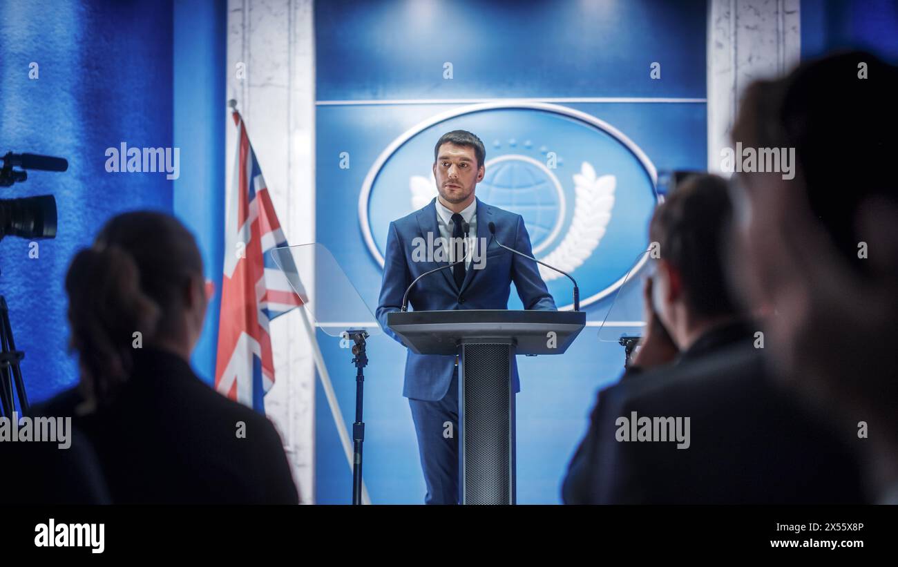 Représentant d'une jeune organisation prenant la parole lors d'une conférence de presse dans le bâtiment du gouvernement. Attaché de presse prononçant un discours au Sommet. Ministre s'adressant au Congrès. Toile de fond avec drapeaux français. Banque D'Images