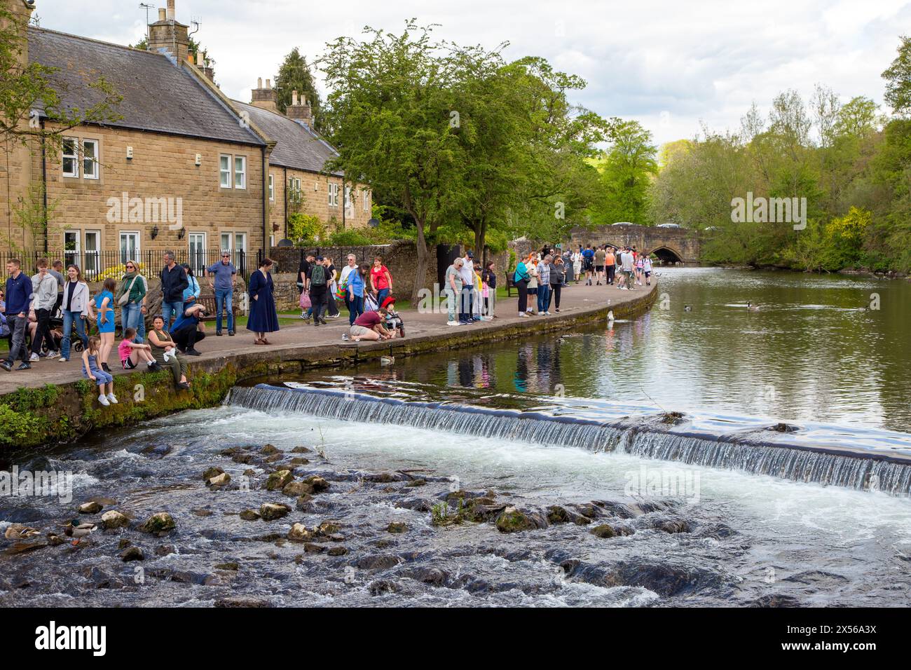 Les gens et les familles apprécient le soleil printanier et le temps ensoleillé sur les rives de la rivière Wye dans la ville de Derbyshire Peak District de Bakewell Banque D'Images