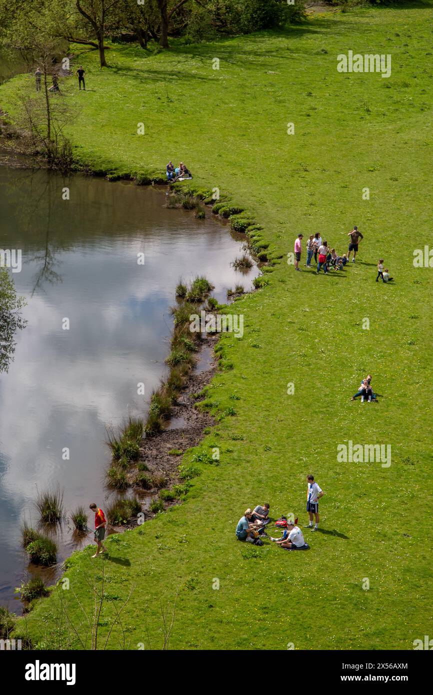 Les gens appréciant le soleil de printemps pique-niquer à Monsal Dale sur les rives de la rivière Wye dans le Peak District anglais à Monsal Head Banque D'Images
