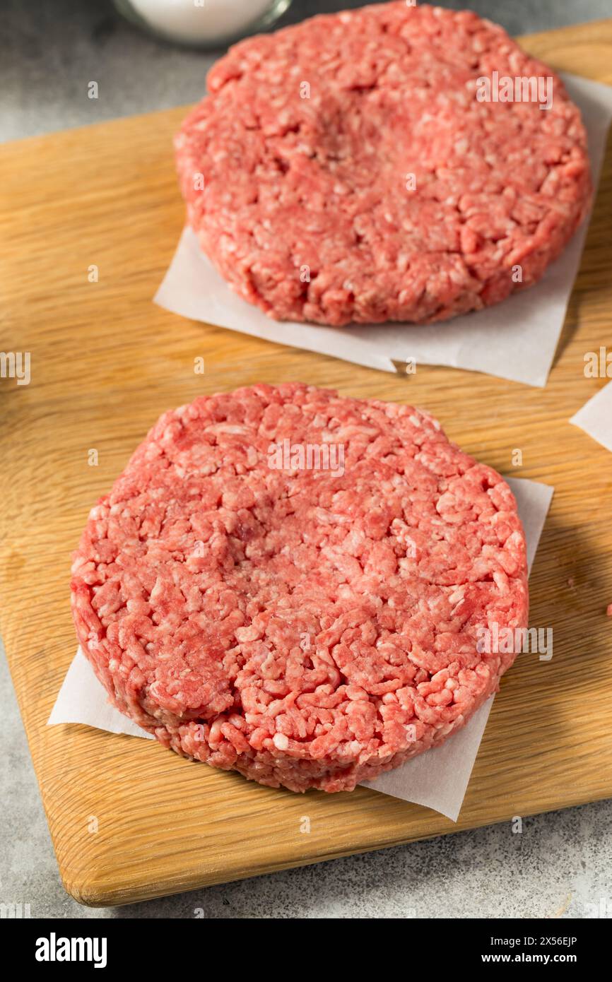 Des hamburgers de bœuf farcis à l'herbe crue prêts à cuire Banque D'Images