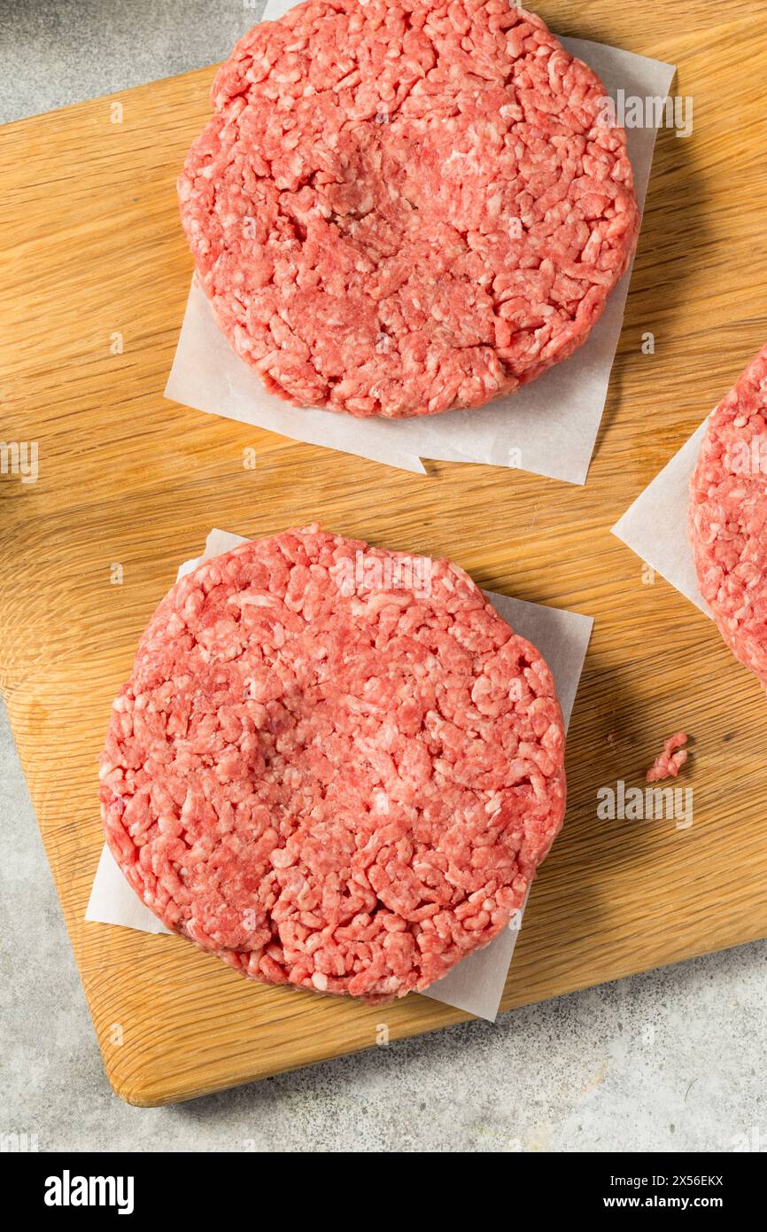 Des hamburgers de bœuf farcis à l'herbe crue prêts à cuire Banque D'Images