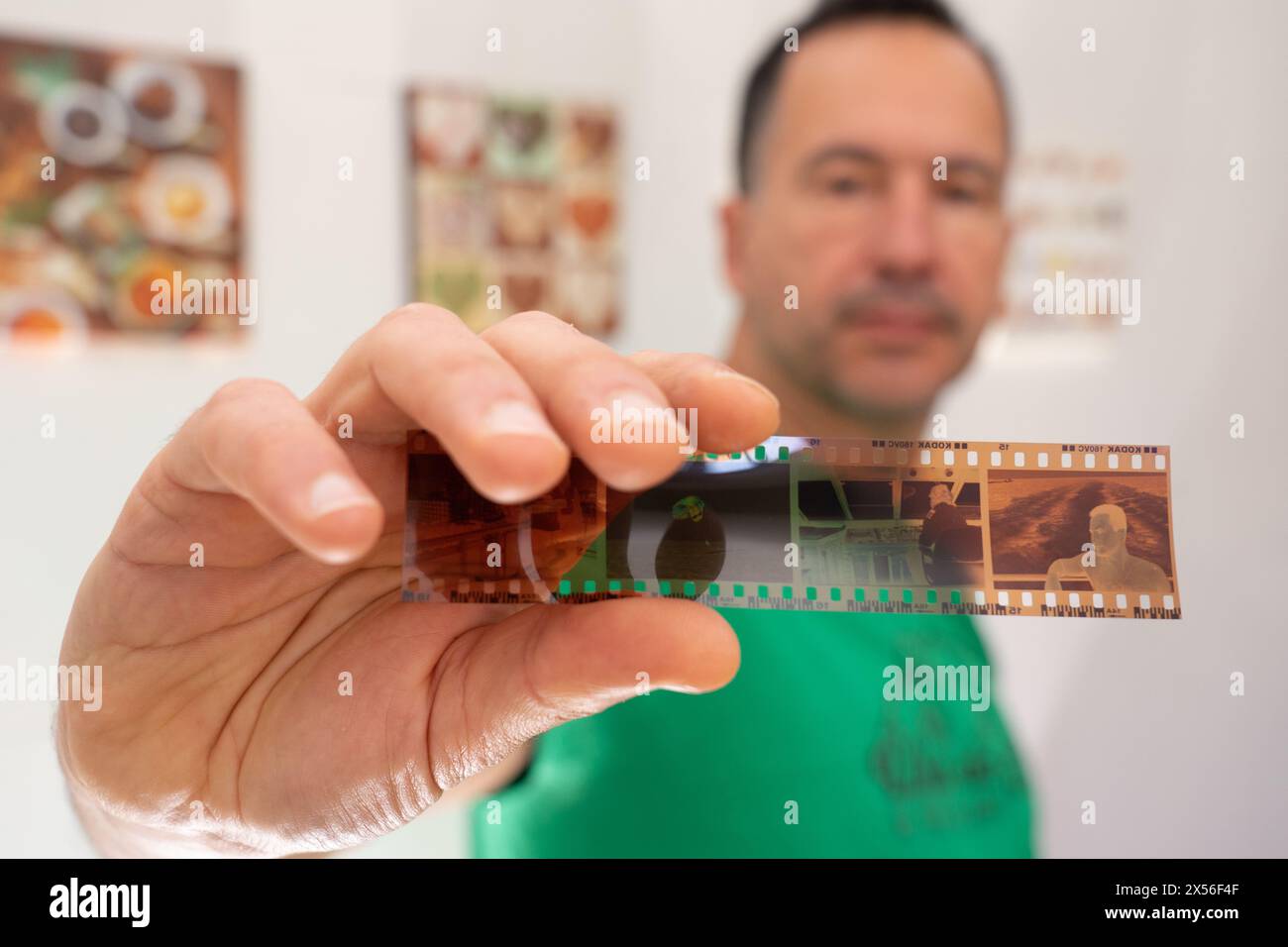 homme blanc de 50 ans montrant un film négatif 35 mm avec son image 30 ans de moins. Banque D'Images