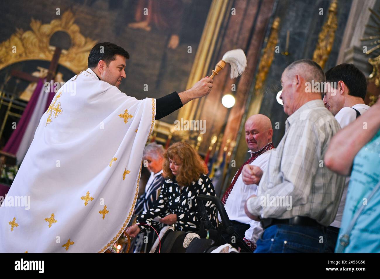 LVIV, UKRAINE - 4 MAI 2024 - Un prêtre bénit les gens et leurs paniers avec de l'eau bénite à l'église Saint Pierre et Paul Garrison le samedi Saint, Lviv, dans l'ouest de l'Ukraine. Banque D'Images