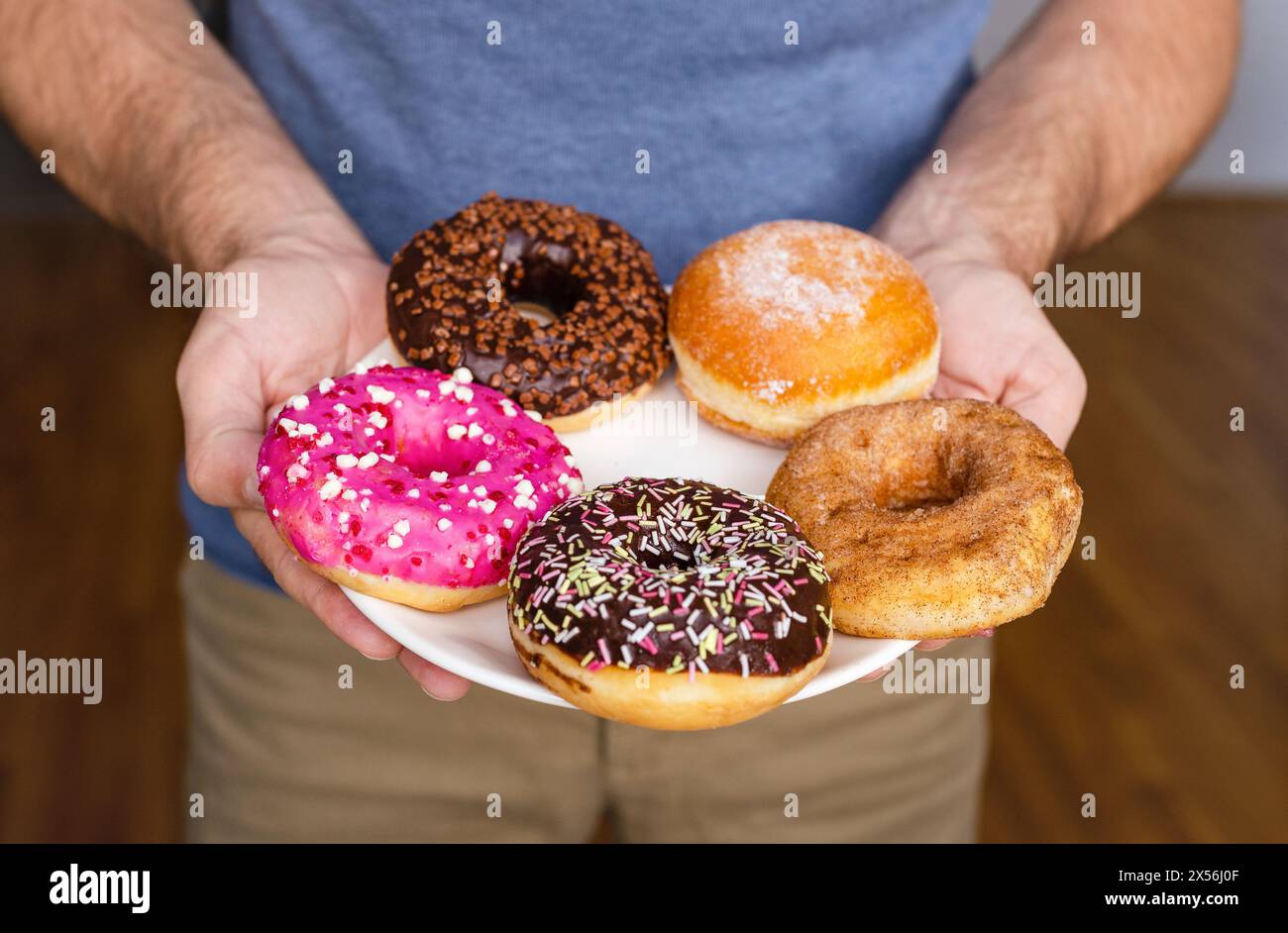 Divers types de beignets sur la plaque gros plan dans les mains de l'homme. Banque D'Images
