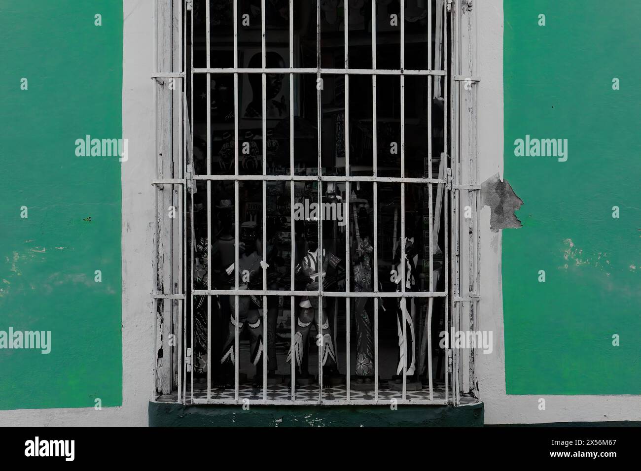 245 Windowshop avec grillades en fer peintes en blanc d'une boutique de souvenirs sur le mur de copeaux vert jade d'une maison coloniale. Trinidad-Cuba. Banque D'Images
