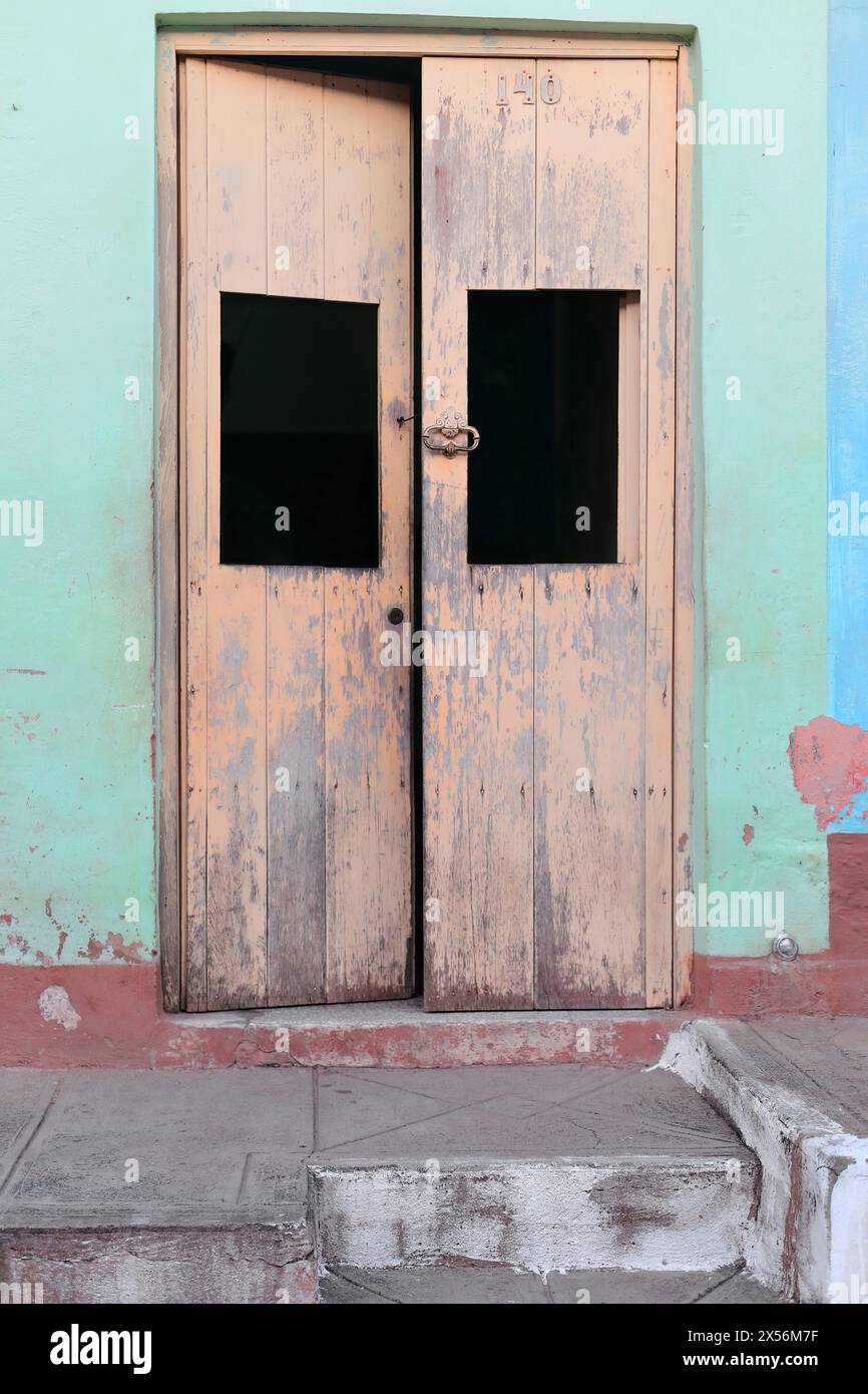 249 porte en bois délavé de couleur beige d'une vieille maison dans la zone Plaza Tres Cruces Square, sur une façade vert menthe écaillée-marron-bleu. Trinidad-Cuba. Banque D'Images