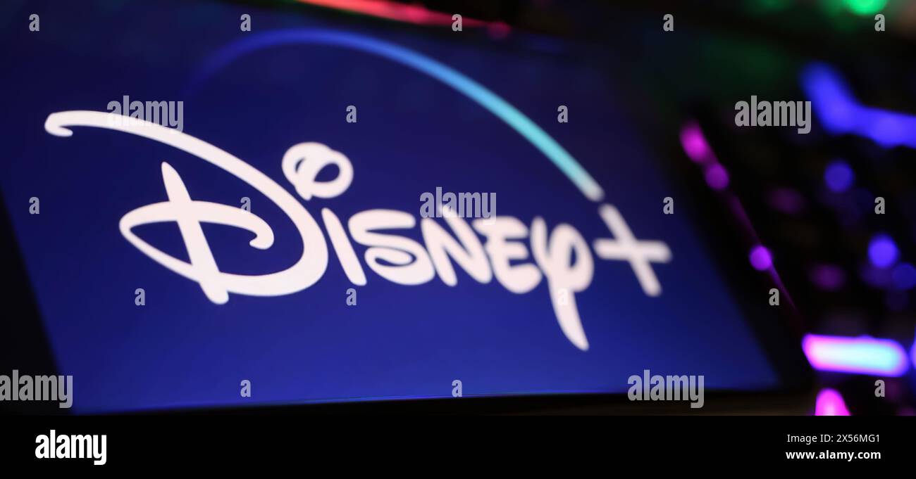 Viersen, Allemagne - 1er mai. 2024 : gros plan de smartphone avec lettrage logo de Disney plus canal de service de streaming sur clavier d'ordinateur Banque D'Images