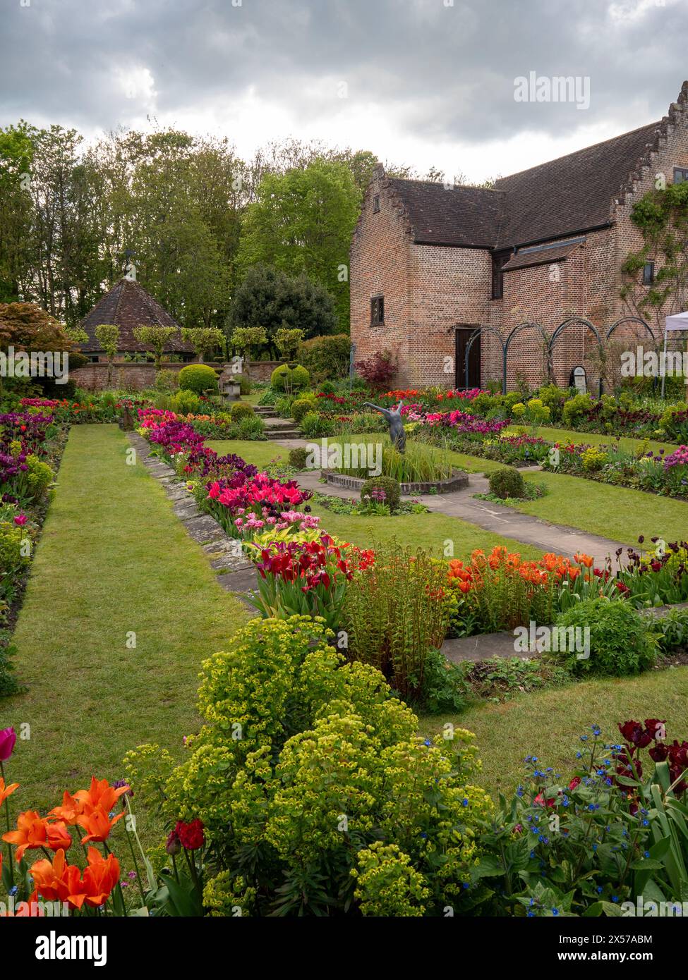 Chenies Manor Sunken Garden vers le Pavillon, ancien bâtiment de pépinière à Tulip Time ; feuillage vert vibrant et variétés de tulipes colorées. Banque D'Images