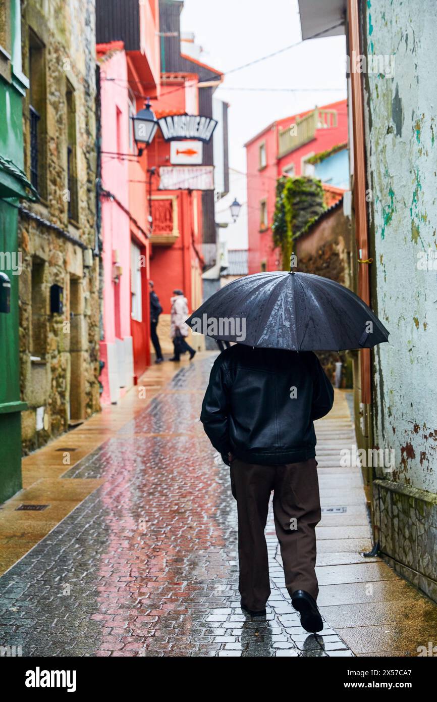 Homme avec parapluie sous la pluie. Finisterre, Fisterra, La Corogne, Galice, Espagne Banque D'Images