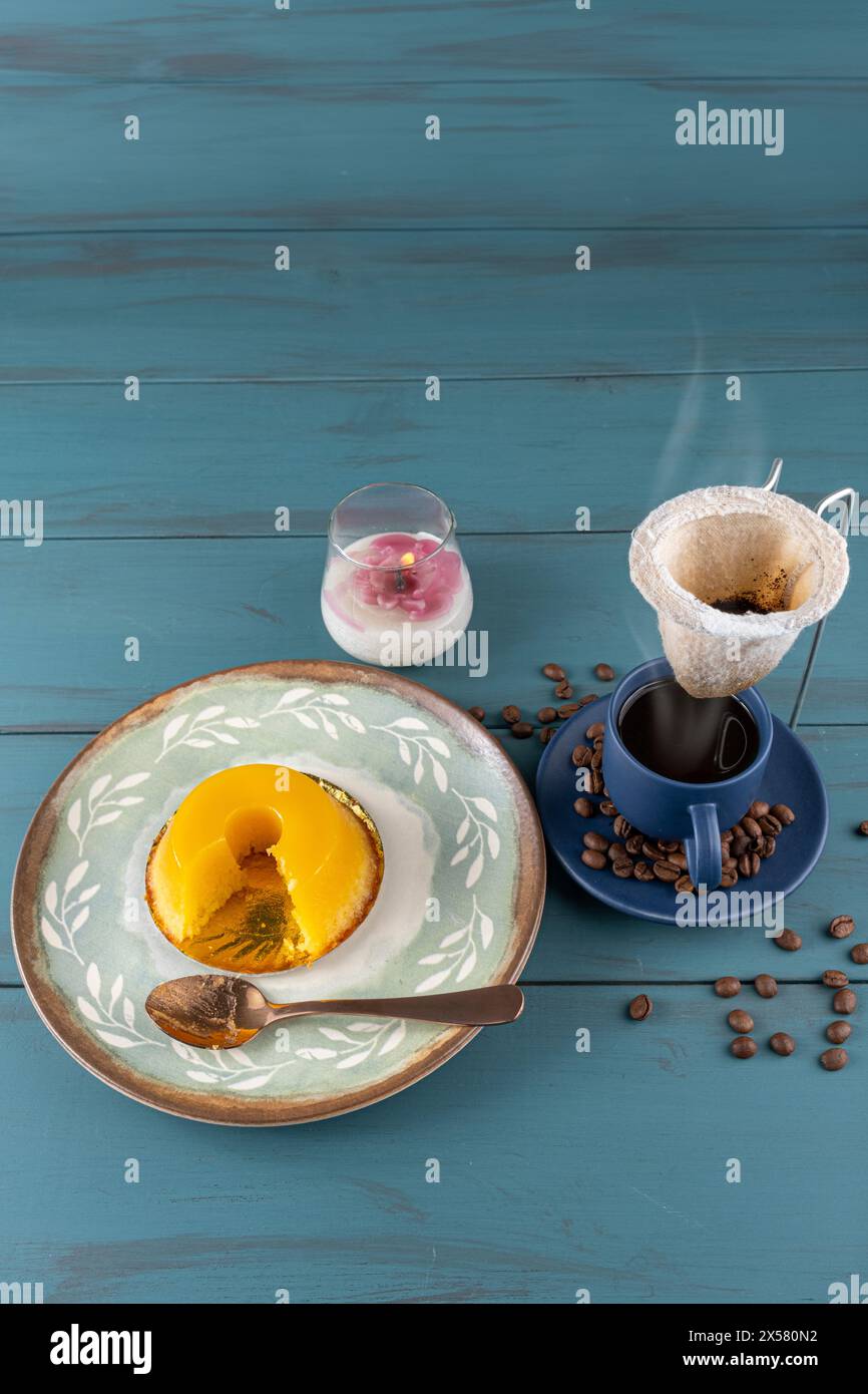 Petit quindim, sucré traditionnel brésilien, à côté d'une cuillère, tasse à café et une bougie 2. Banque D'Images