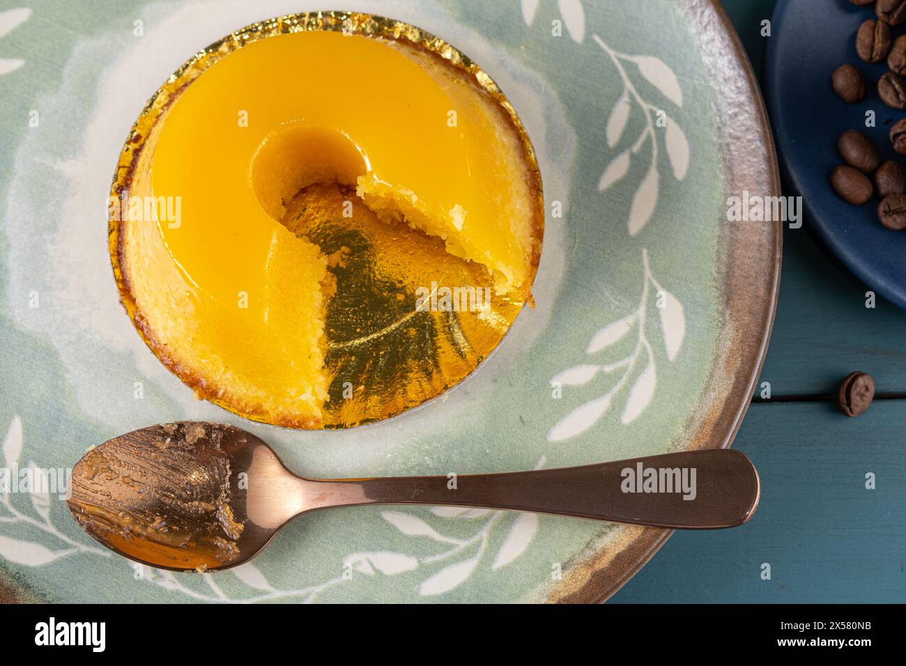 Petit quindim, sucré traditionnel brésilien, à côté d'une cuillère, tasse à café et une bougie 5. Banque D'Images