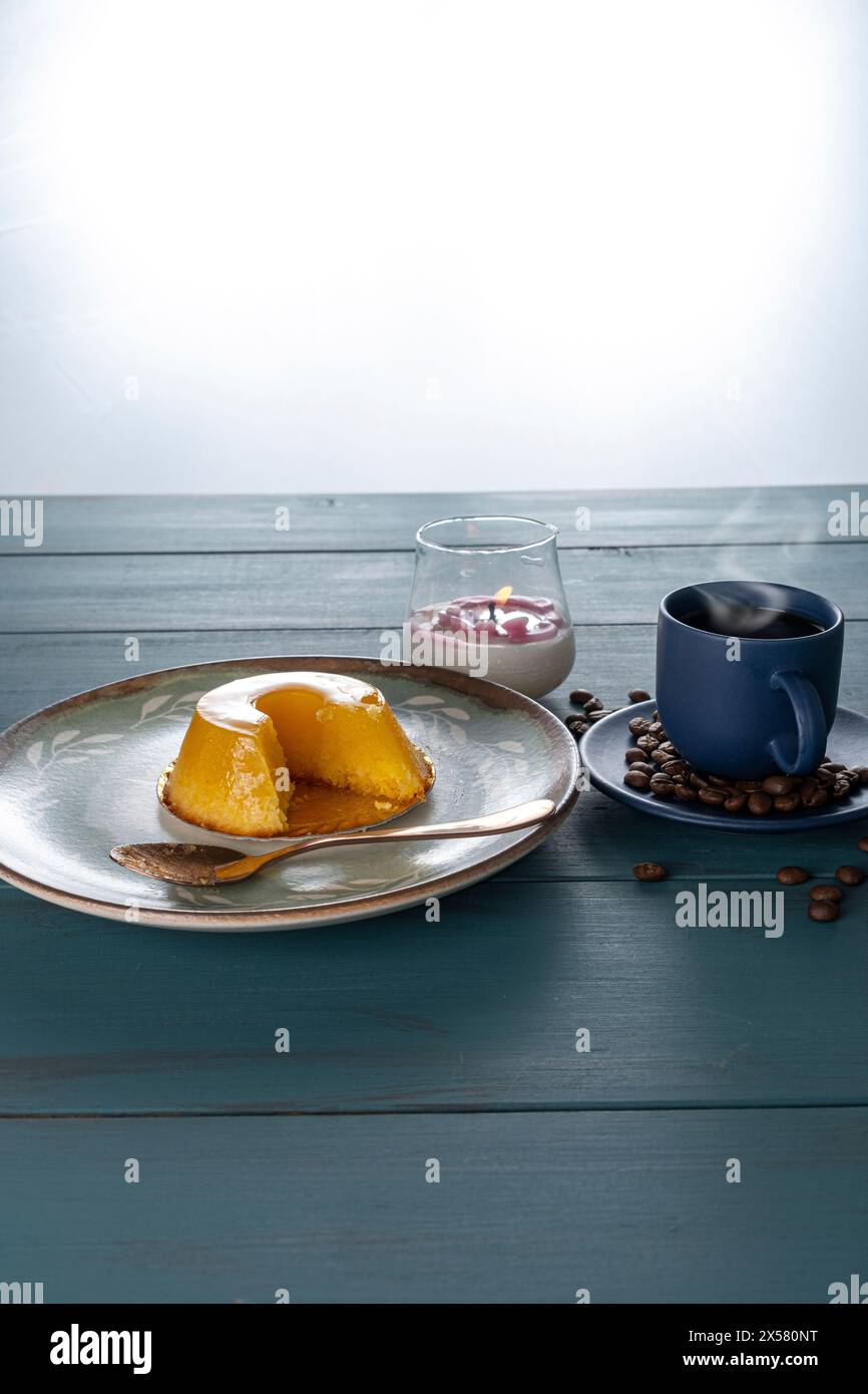 Petit quindim, sucré traditionnel brésilien, à côté d'une cuillère, tasse à café et une bougie 9. Banque D'Images