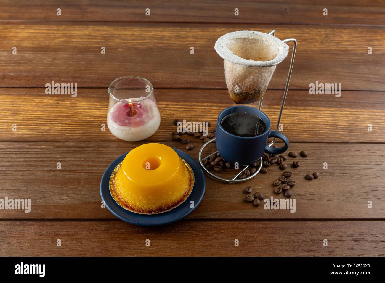 Petit quindim, sucré traditionnel brésilien, à côté d'une tasse de café et d'une bougie 1. Banque D'Images