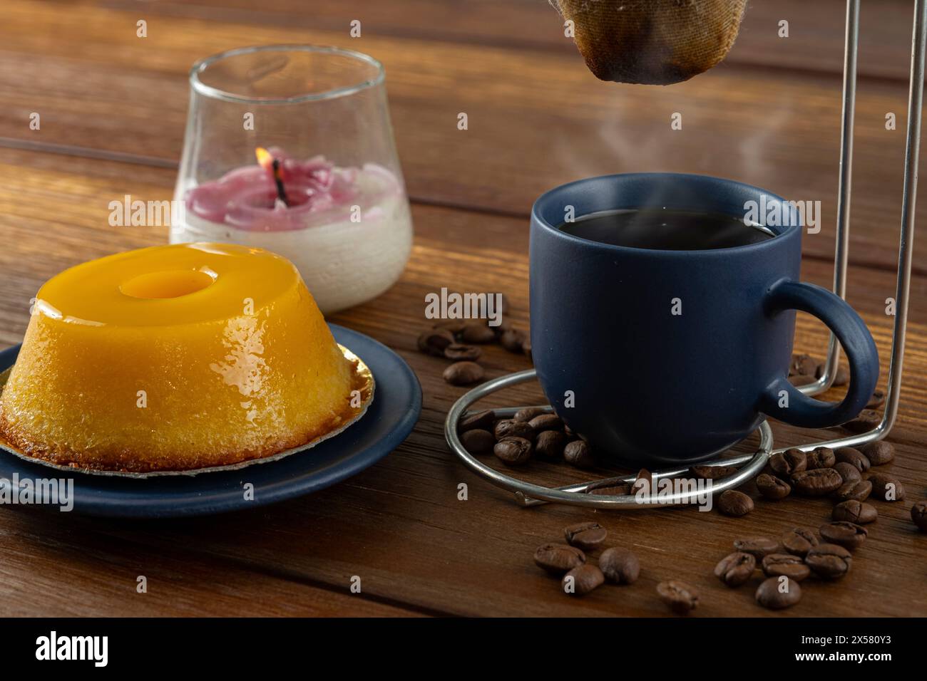 Petit quindim, sucré traditionnel brésilien, à côté d'une tasse de café et d'une bougie 5. Banque D'Images
