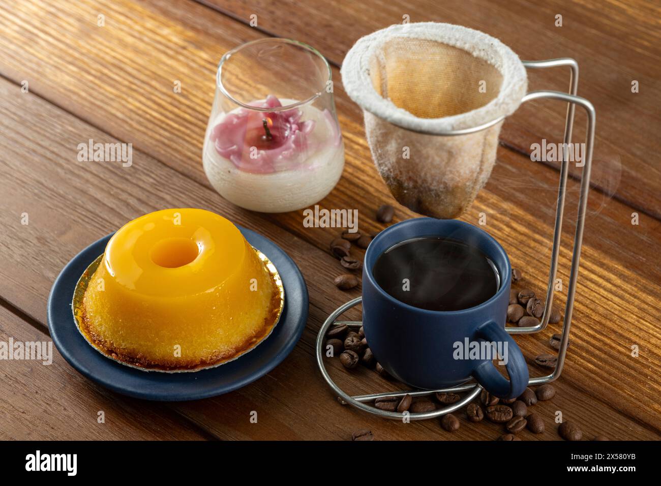 Petit quindim, sucré traditionnel brésilien, à côté d'une tasse de café et d'une bougie 8. Banque D'Images