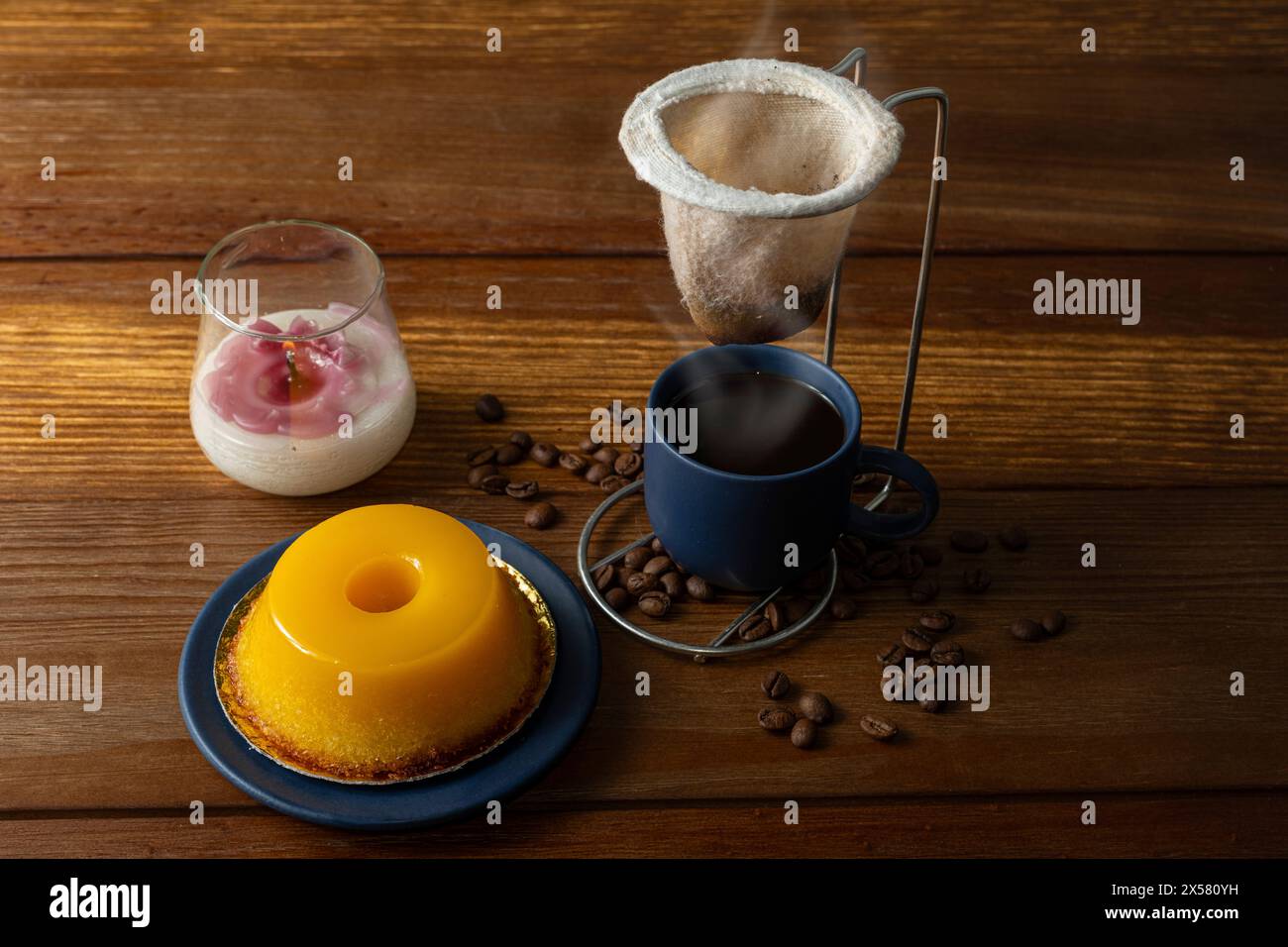 Petit quindim, sucré traditionnel brésilien, à côté d'une tasse de café et d'une bougie 10. Banque D'Images