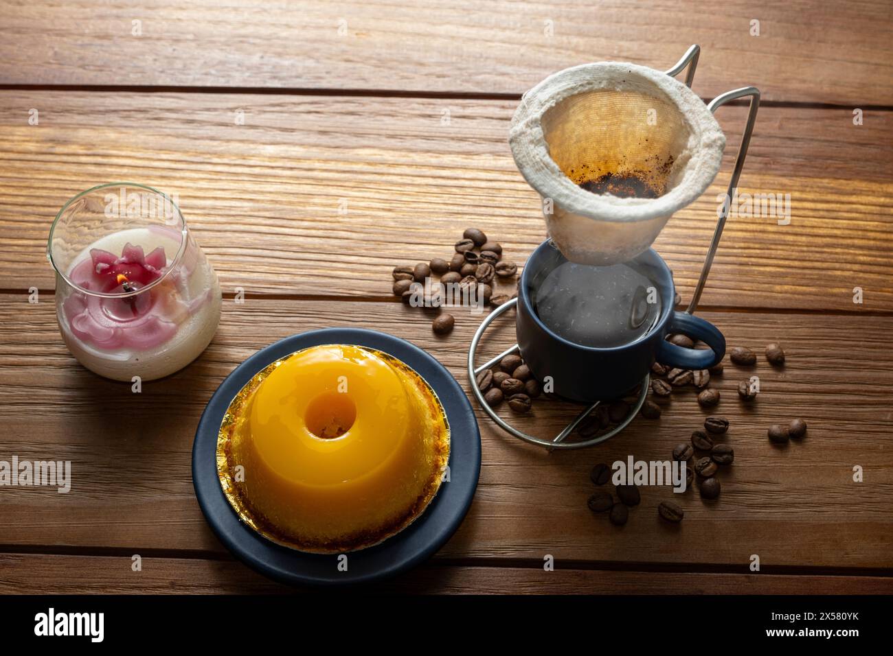 Petit quindim, sucré traditionnel brésilien, à côté d'une tasse de café et d'une bougie 11. Banque D'Images