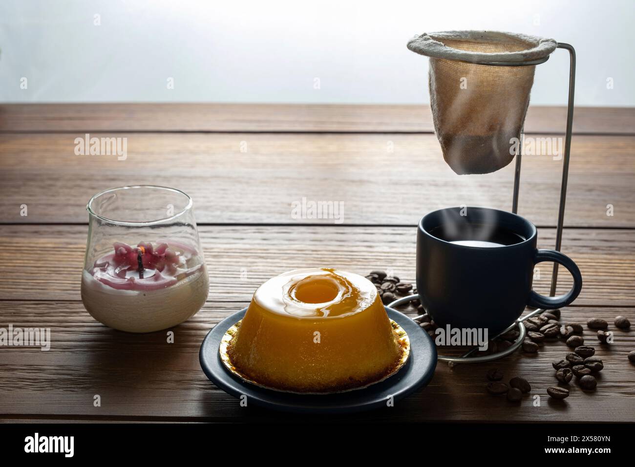 Petit quindim, sucré traditionnel brésilien, à côté d'une tasse de café et d'une bougie 12. Banque D'Images