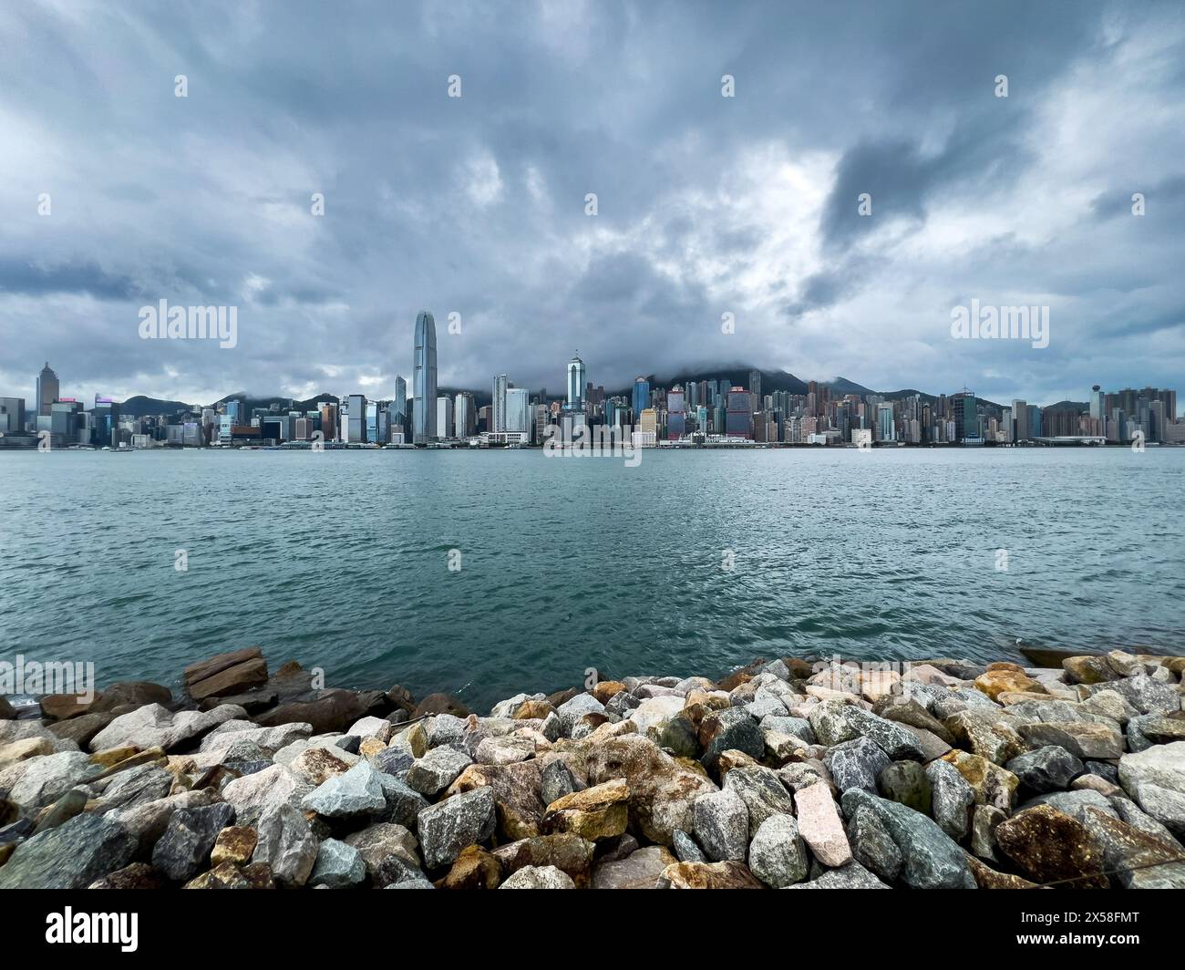 Vue panoramique de l'île de Hong Kong depuis Kowloon. Limpide après des semaines de pluie. Brise-lames en pierre au premier plan. Mer bleu acier. Banque D'Images