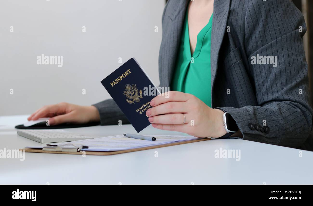 Gros plan d'une femme caucasienne tenant un passeport américain à la table du bureau Banque D'Images