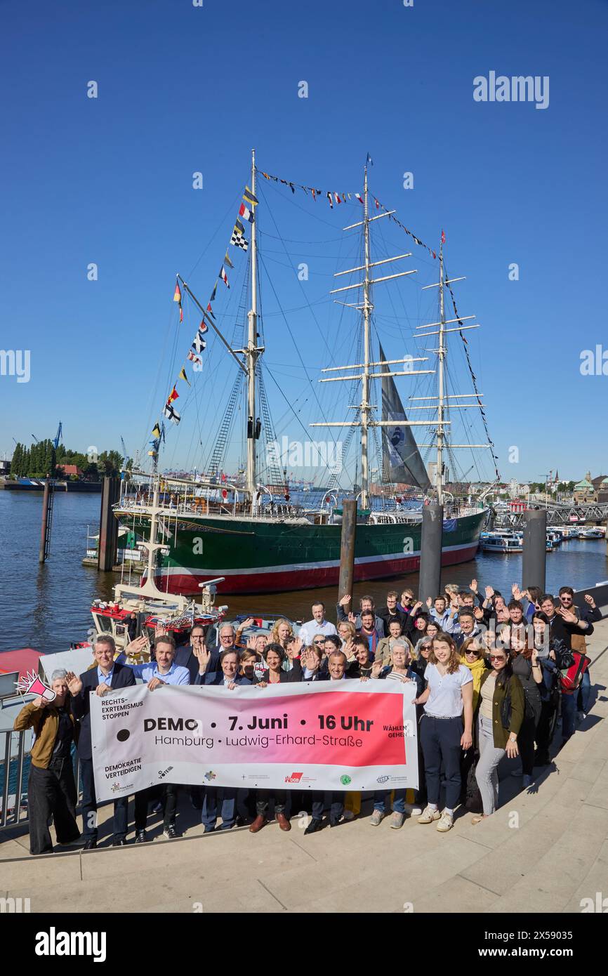 Hambourg, Allemagne. 08 mai 2024. Les participants à une séance photo de l'alliance de Hambourg 'Stop à l'extrémisme de droite - défendre la démocratie - aller voter' se tiennent dans le port sur Jan-Fedder-Promenade et tiennent une banderole avec l'inscription 'Demo 7 juin, 16 heures Hambourg Ludwig-Erhard-Straße'. Le musée et le navire monument Rickmer Rickmers peuvent être vus en arrière-plan. Crédit : Georg Wendt/dpa/Alamy Live News Banque D'Images