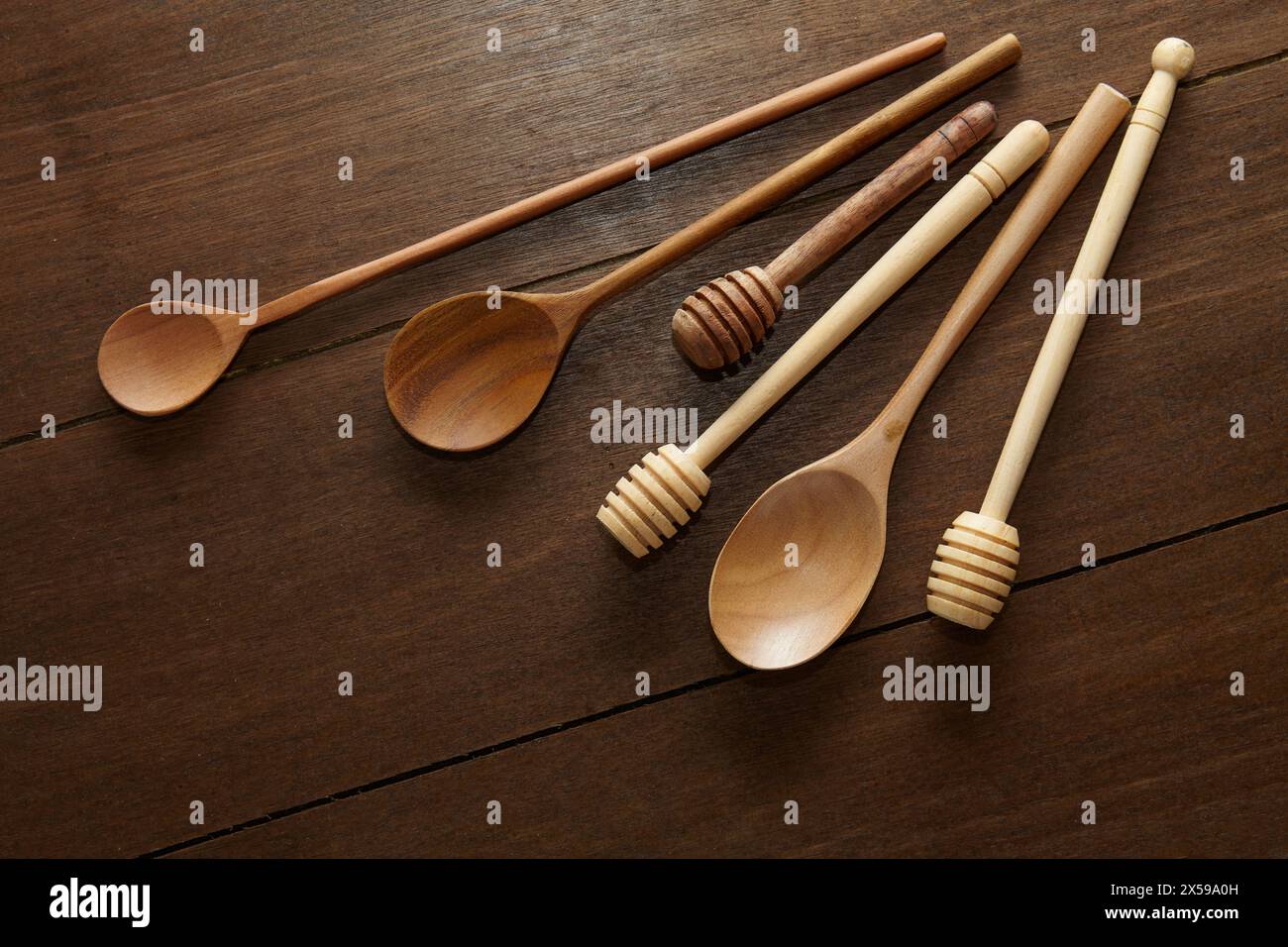 Plusieurs cuillères en bois et des trempettes en bois de miel de différentes tailles sur une table en bois Banque D'Images