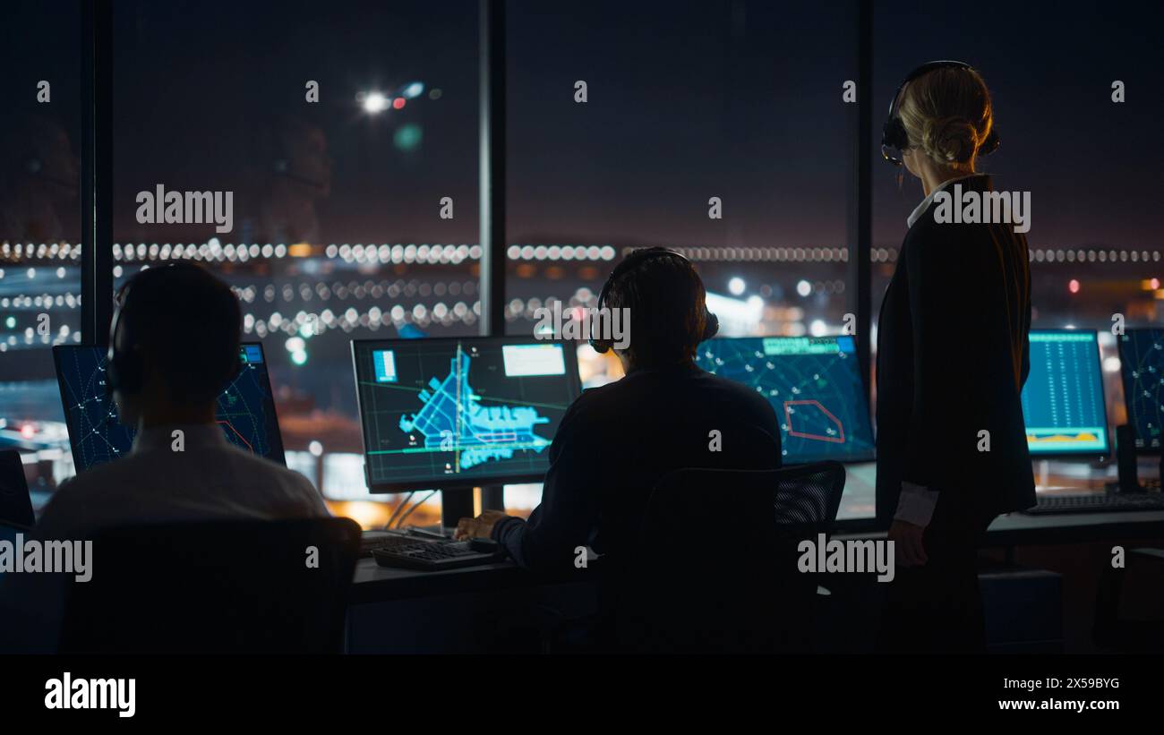 Les contrôleurs aériens masculins et féminins avec casques parlent dans la tour de l'aéroport la nuit. Salle de bureau remplie d'écrans d'ordinateur de bureau avec écrans de navigation, données radar de vol d'avion pour les contrôleurs. Banque D'Images