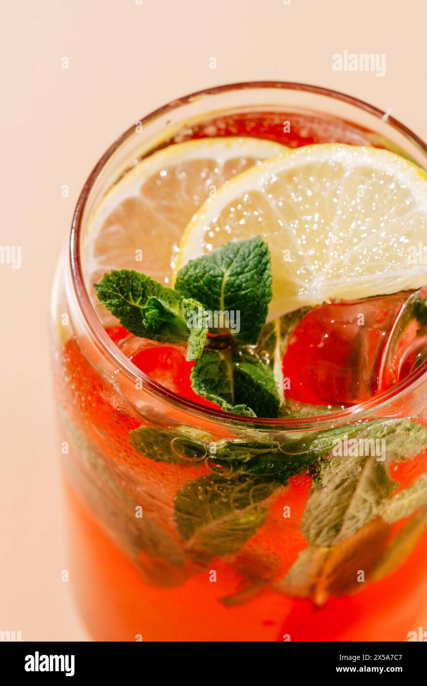 Limonade aux baies et à l'orange vives garnie de feuilles de menthe fraîche et de tranches de citron, servie dans un verre avec de la glace ; parfait pour une journée chaude. Banque D'Images