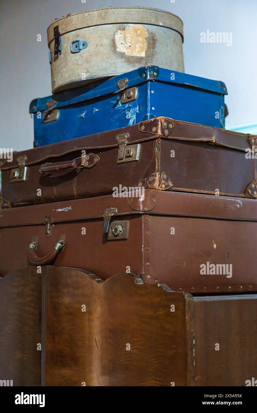 Une collection de valises vintage usées et en lambeaux est empilée, présentant différentes couleurs et tailles, évoquant un sens de l'histoire du voyage et de la nostalgie. Banque D'Images