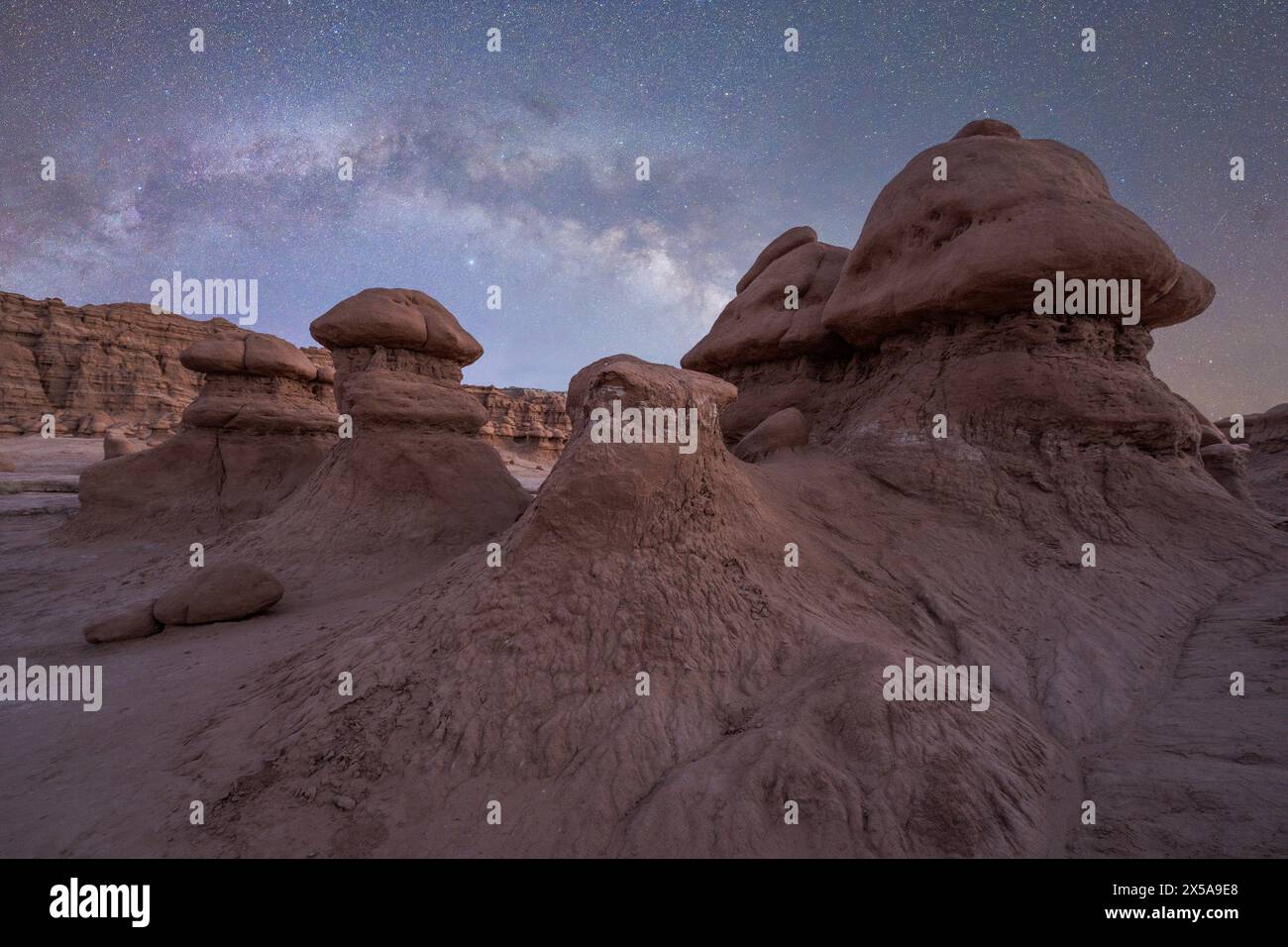 Le ciel étoilé illumine les hoodoos uniques du parc d'État de Goblin Valley, Utah, avec l'arc de la voie lactée visible dans la nuit sereine. Banque D'Images