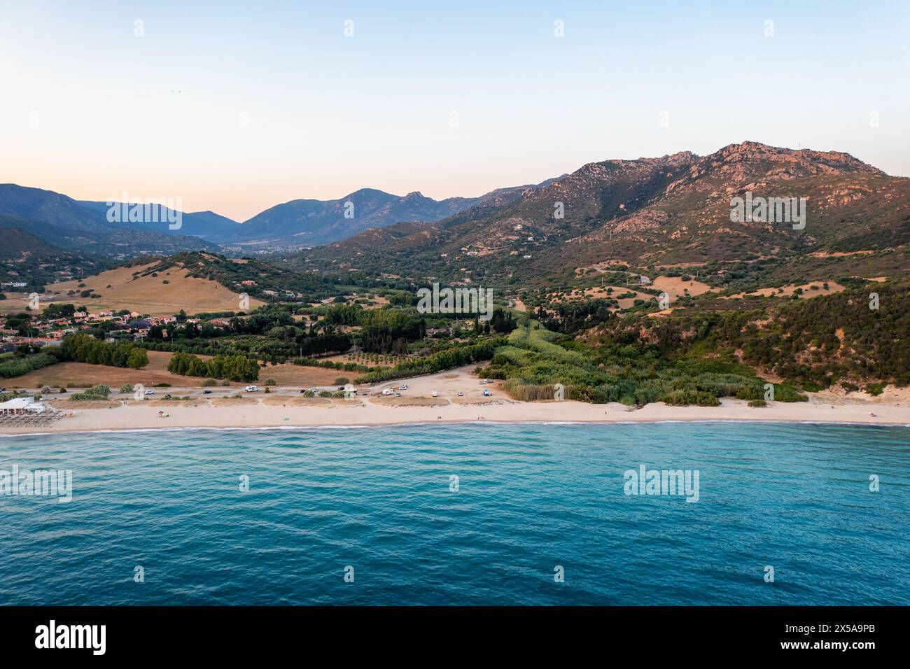 Une prise de vue aérienne époustouflante capture le coucher de soleil serein sur la pittoresque côte sarde, avec ses collines et ses eaux Azur, la plage de Porto Giunco Banque D'Images