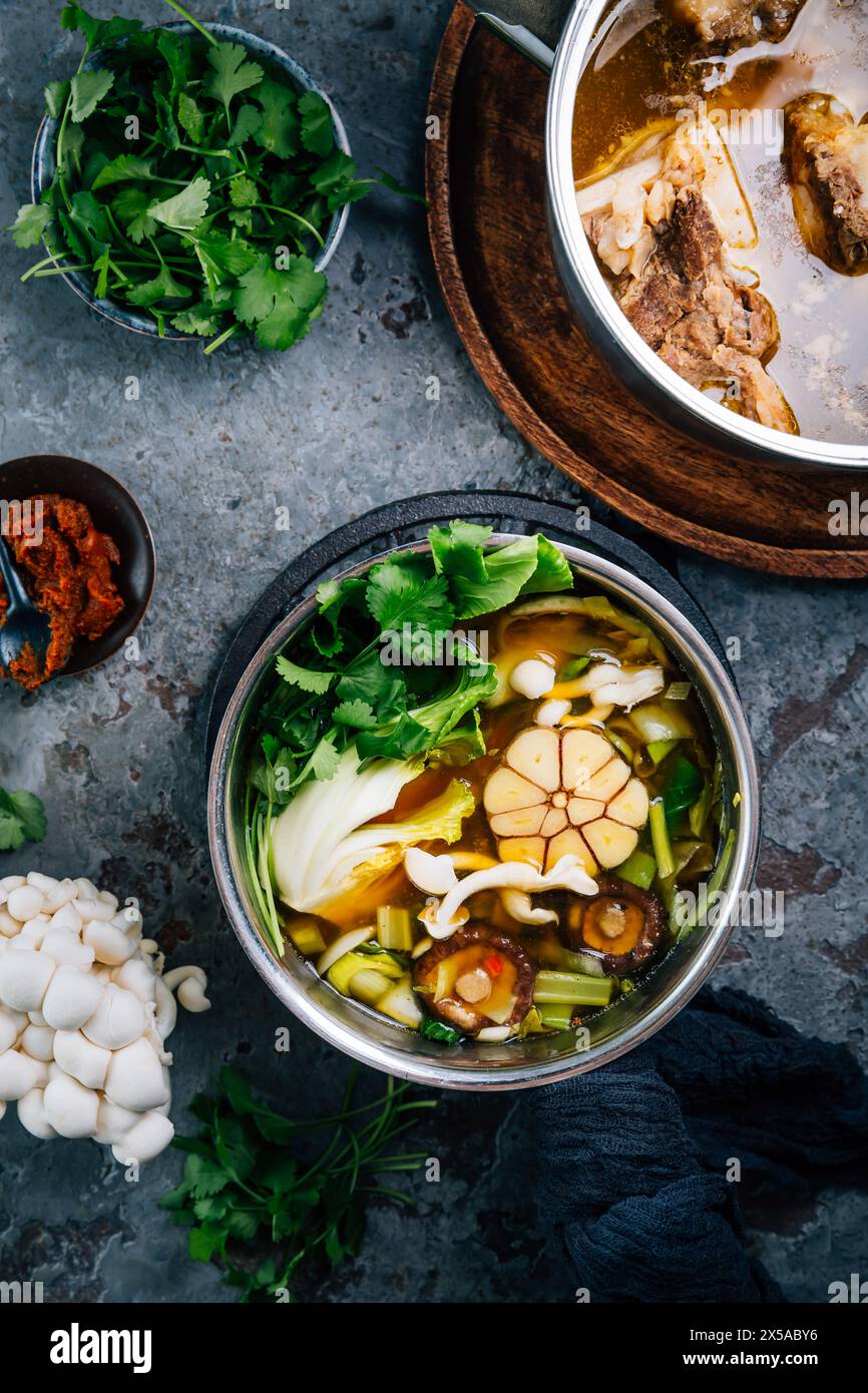 Bouillon de légumes maison avec bouillon d'os de bœuf dans des pots avec des ingrédients Banque D'Images