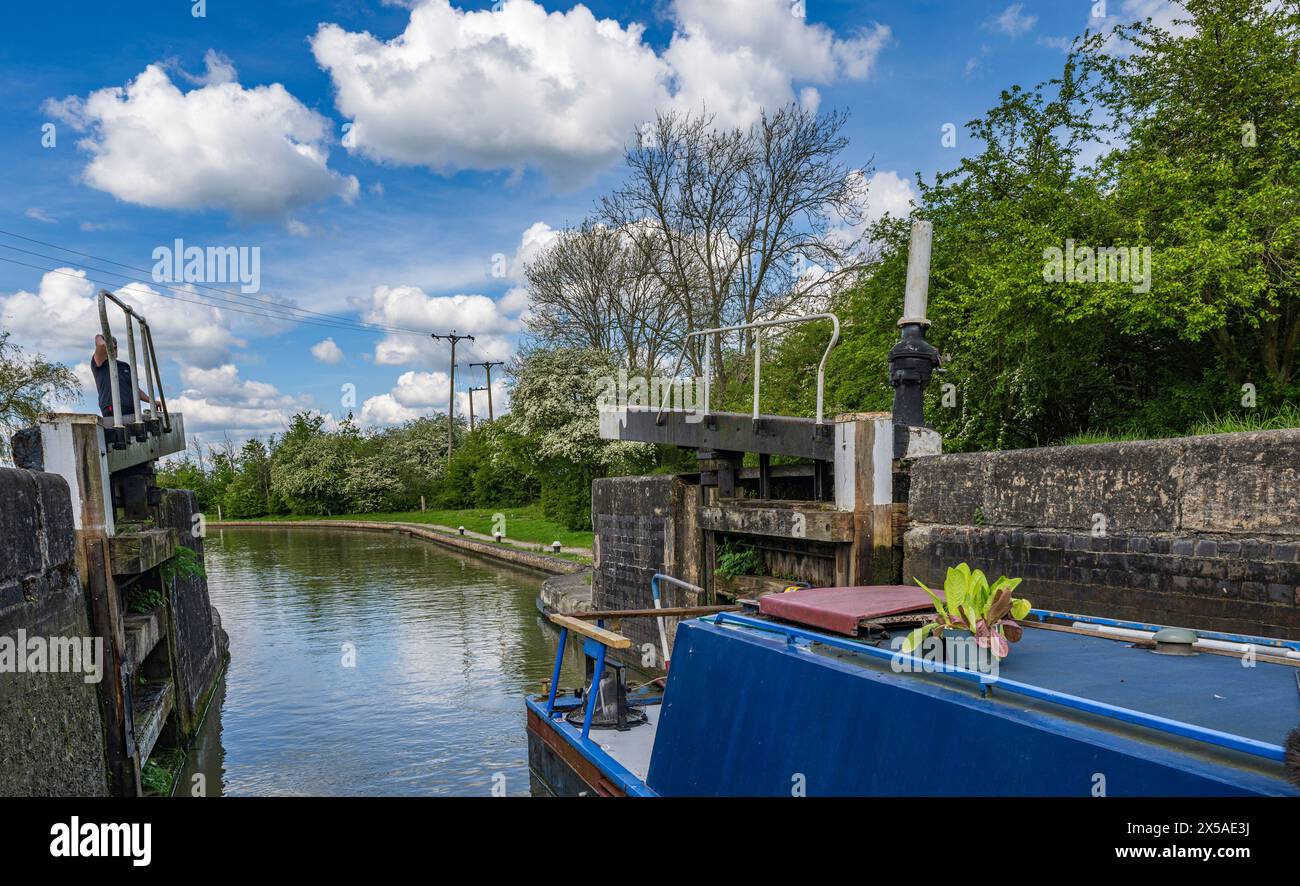 Grand Union canal main Line, Calcutt Locks, Angleterre – Un bateau étroit dans l'écluse supérieure avec les portes d'écluse fermant par une journée d'été ensoleillée brillante contre un ciel bleu Banque D'Images