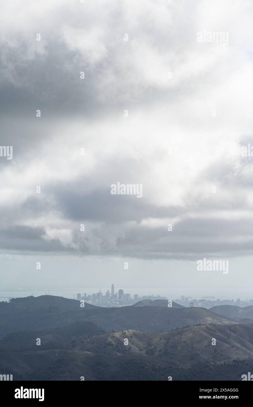 Vue lointaine de la skyline de San Francisco, vue à travers le brouillard et la brume depuis le sommet d'une montagne verte printanière dans les Marin Headlands, au nord de Cali Banque D'Images