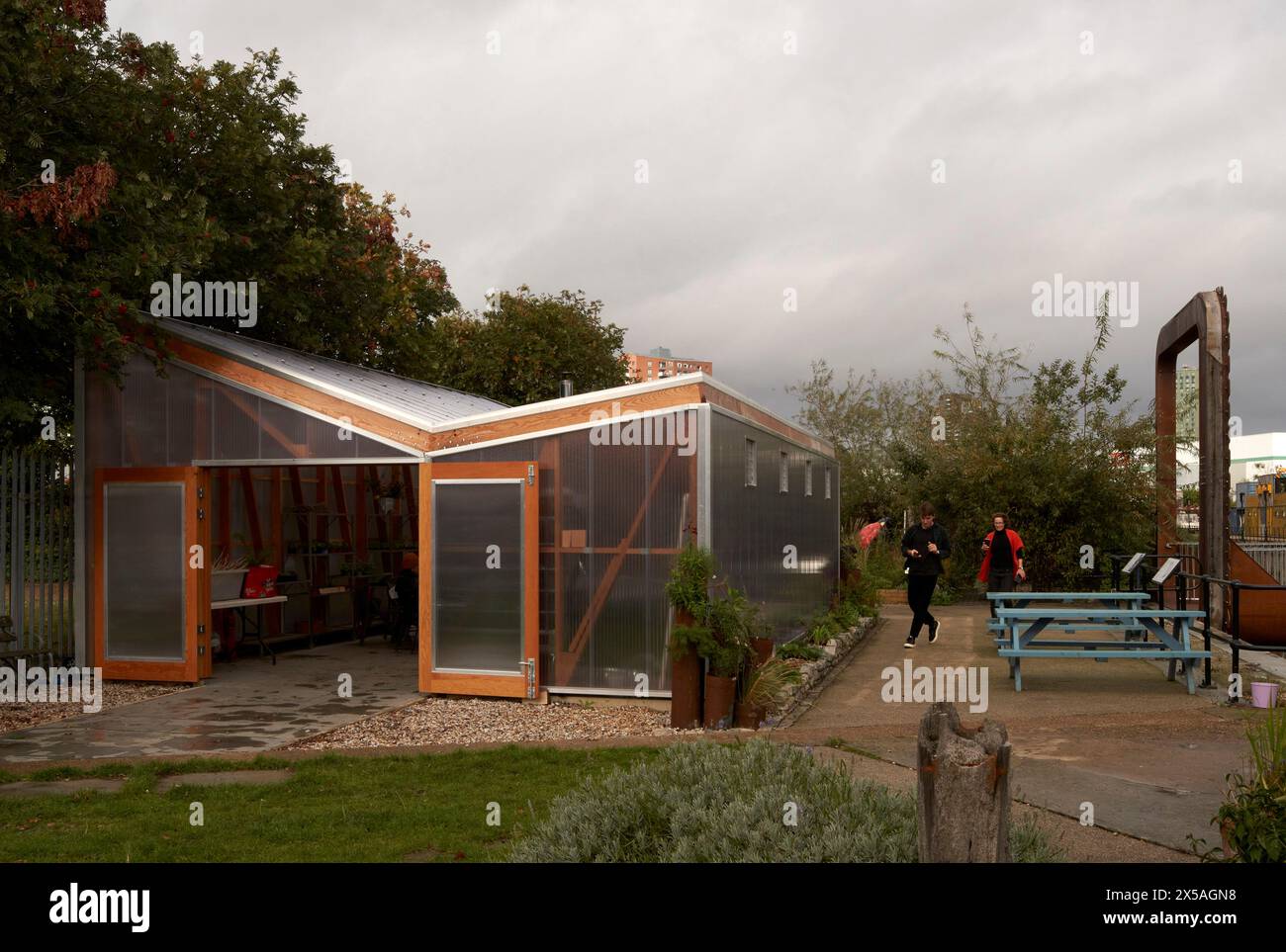 Élévation avant de la façade d'entrée translucide avec porte ouverte, les étudiants arrivant. Cody Dock - The Growing Space, Londres, Royaume-Uni. Architecte : Li Banque D'Images