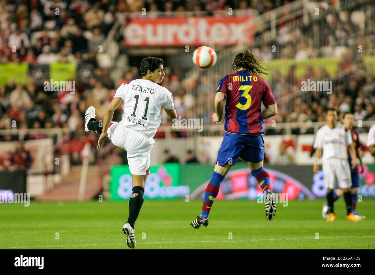 Renato et Milito sautent pour un ballon haut dans un match crucial de la Liga. Banque D'Images