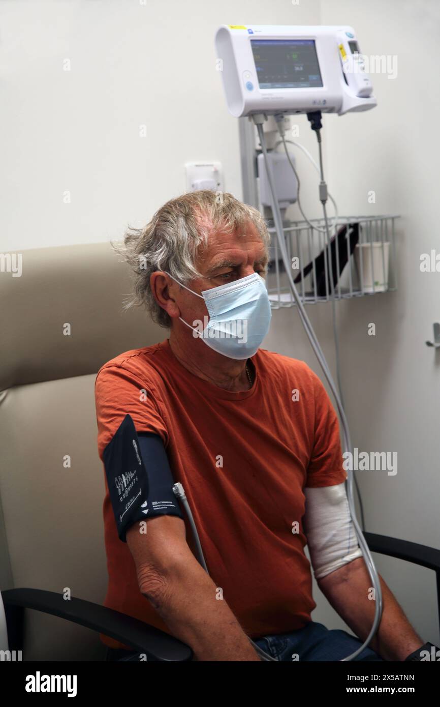 Patient portant un masque facial ayant subi un test de pression artérielle avant un traitement de chimiothérapie à l'hôpital Surrey Angleterre Banque D'Images