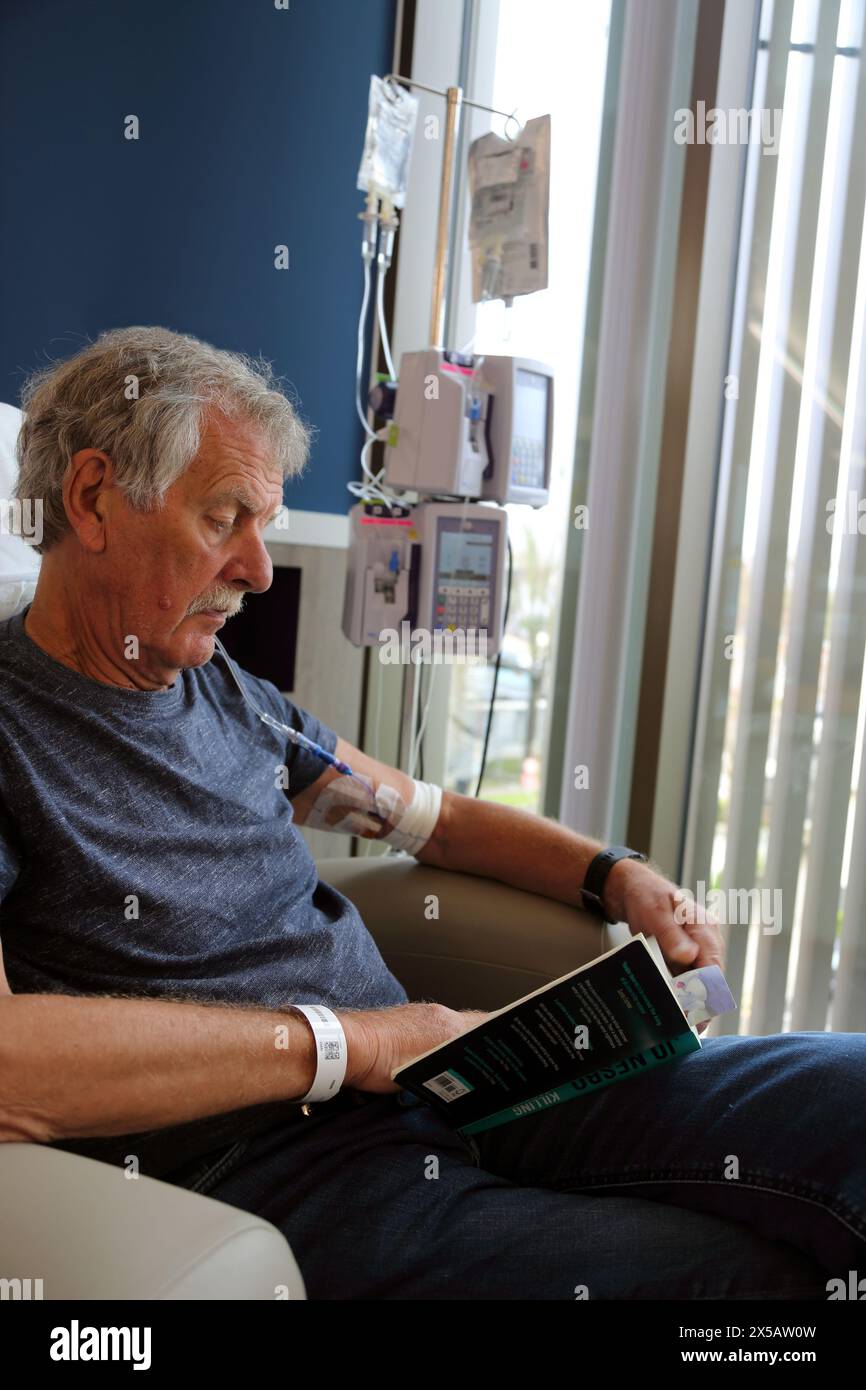 Cancer patient Reading Book tout en ayant un traitement de chimiothérapie avec perfusion intraveineuse pompe de chimiothérapie Surrey Angleterre Banque D'Images