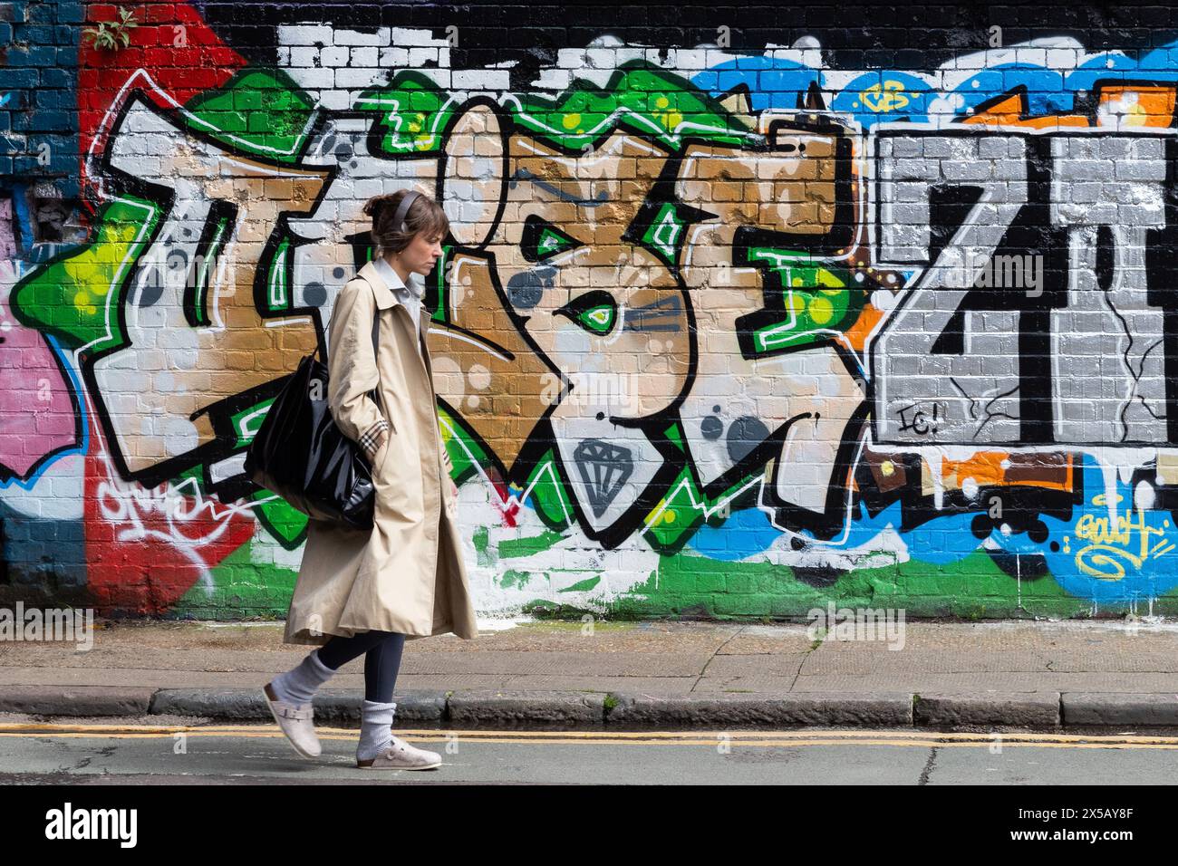 Londres, Royaume-Uni. 7 mai 2024. Un membre du public passe devant une section de mur présentant plusieurs couches d'art de rue à Shoreditch. Murs dans et aro Banque D'Images