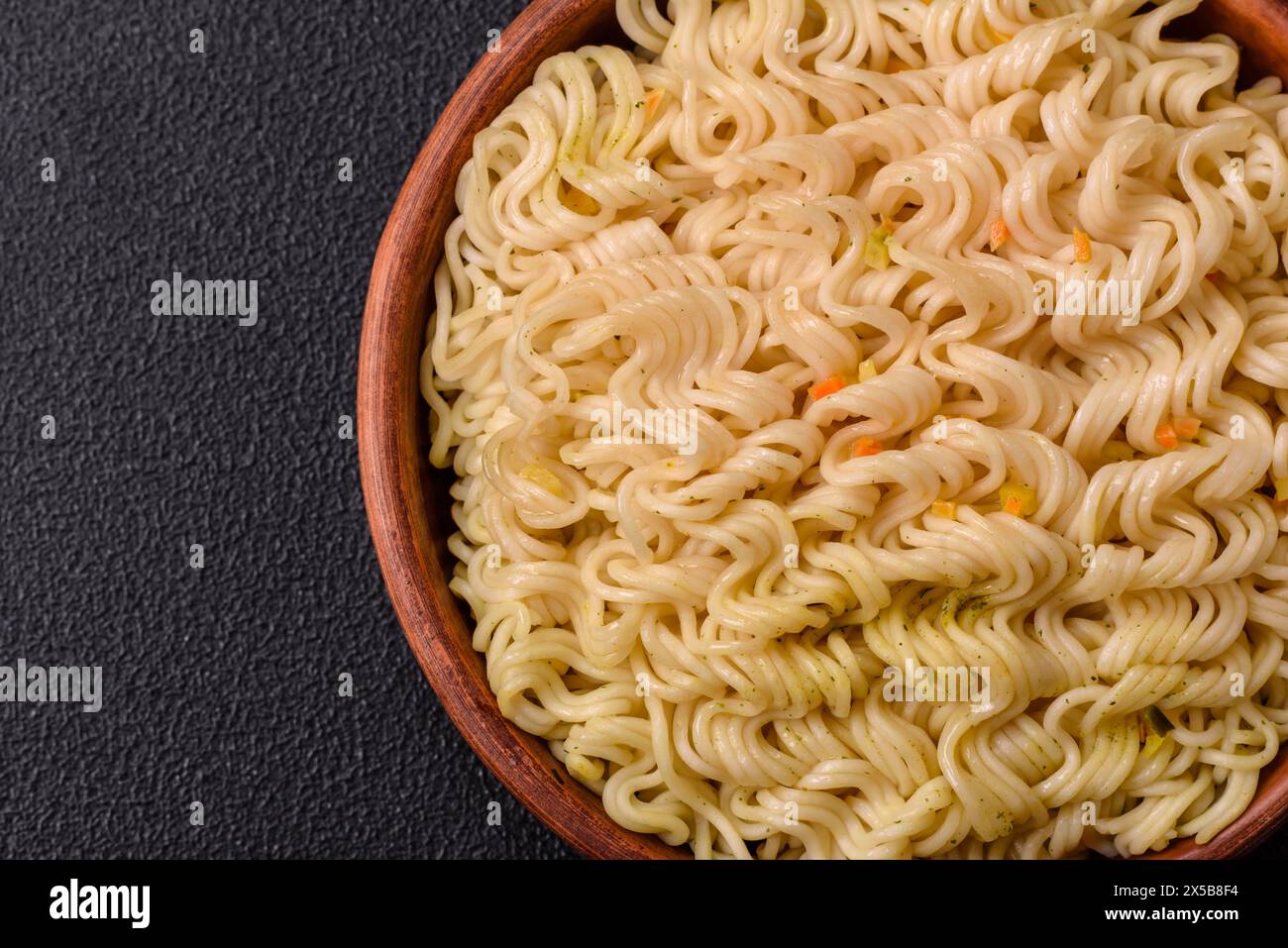 Délicieux plat asiatique nouilles de riz ou udon avec des légumes, des épices et des herbes sur un fond de béton foncé Banque D'Images