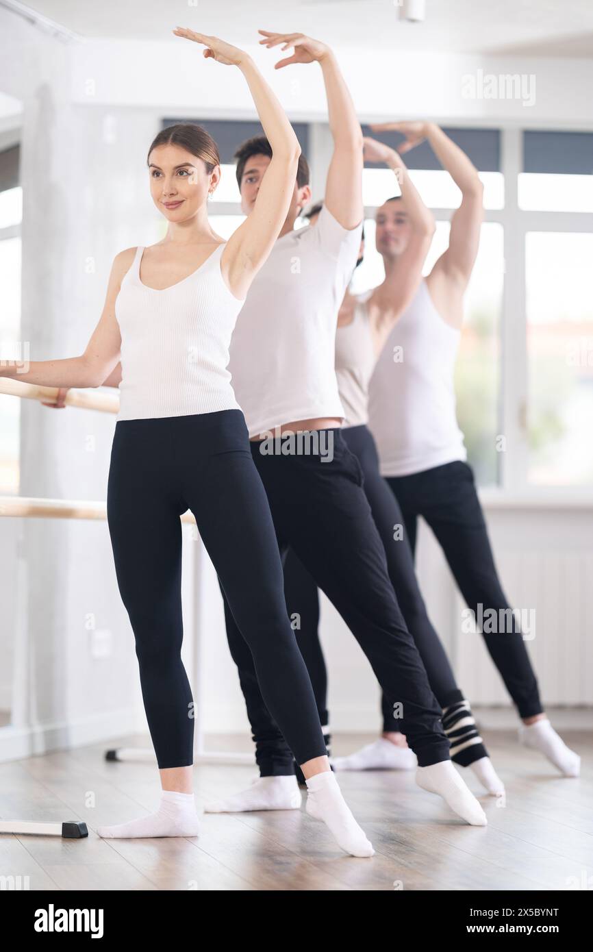Femme exécutant le tendu de combat à la séance de fitness de barre de groupe Banque D'Images