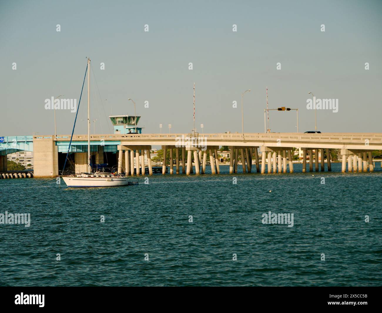 Large vue sud-est de St Pete Beach Community Center vers Corey Causeway pont-levis Boca Ciega Bay avec voilier pas de mât dans le coucher du soleil d'eau bleue Banque D'Images