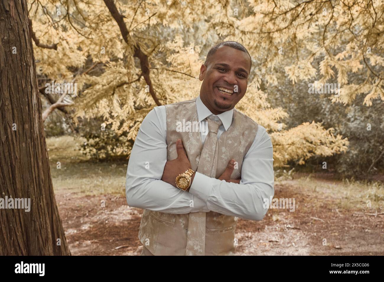 Homme latino souriant à la caméra, il se tient debout, les bras croisés. Concept de saison d'automne, l'homme est heureux. Banque D'Images