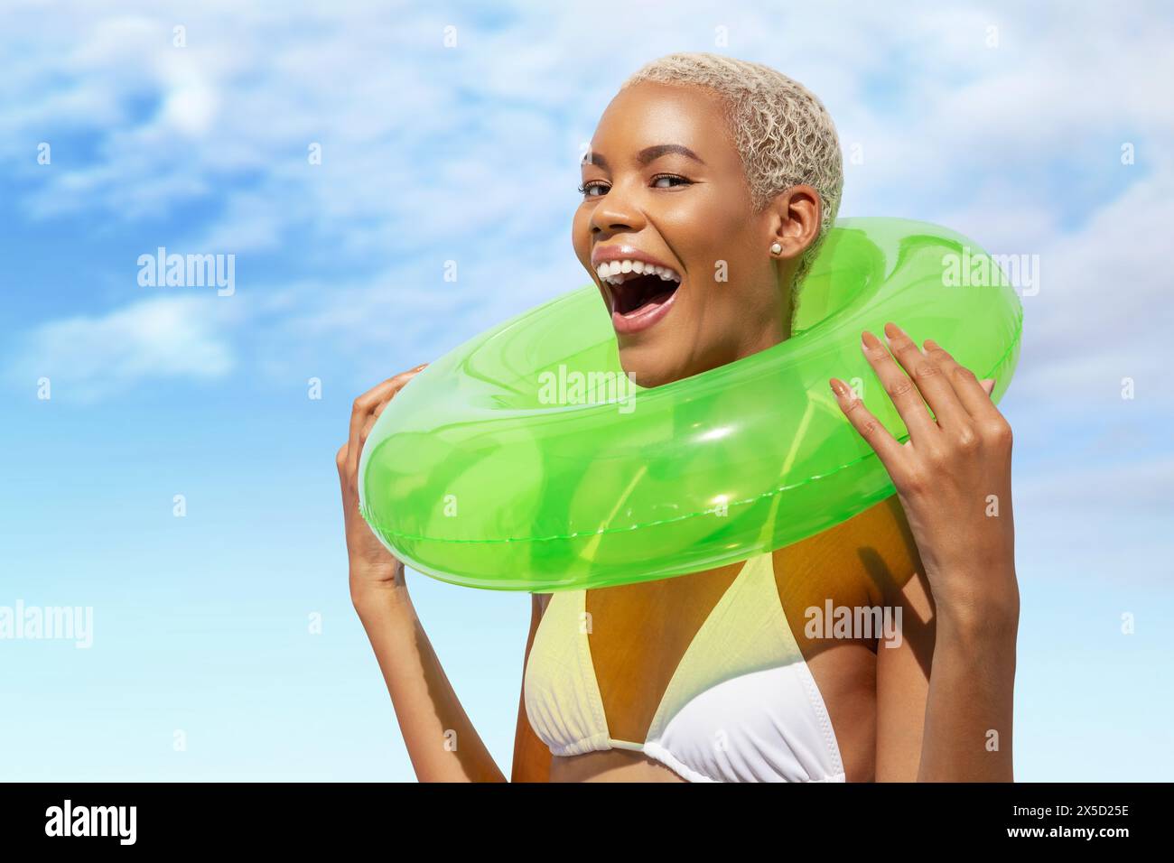 Joyeux rire amusant jeune femme tenant l'anneau vert de nage, femme africaine latino-américaine dans la journée ensoleillée d'été avec le ciel bleu. Concept de vacances balnéaires, Banque D'Images