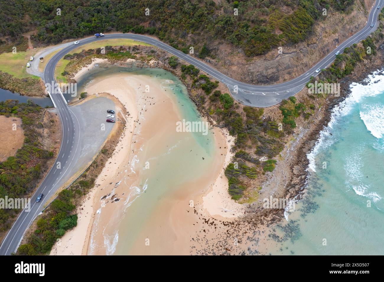 Vue aérienne d'une route serpentant autour d'un littoral spectaculaire et de l'embouchure d'une rivière à Lorne sur la Great Ocean Road à Victoria, en Australie. Banque D'Images