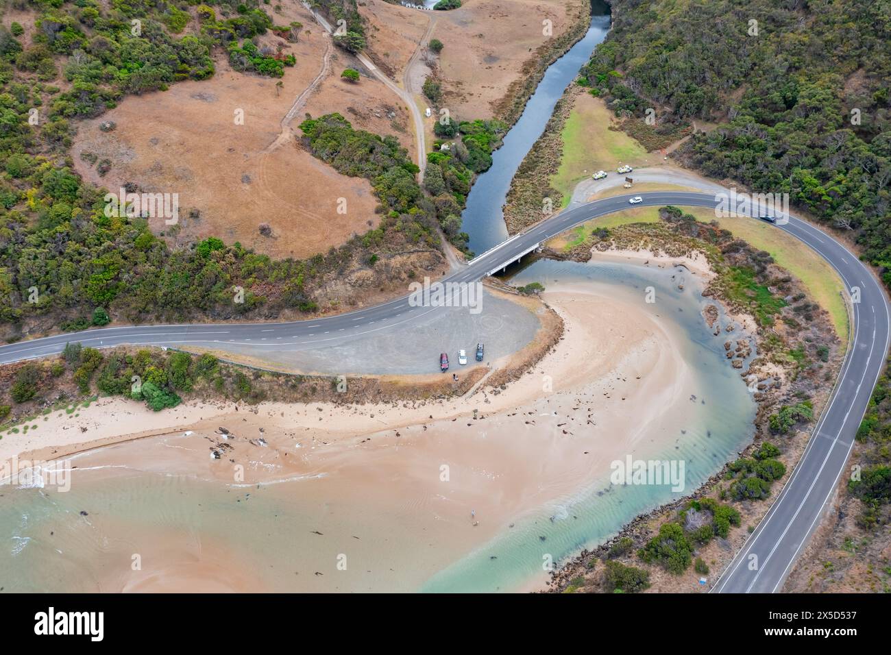 Vue aérienne d'une route serpentant autour d'un littoral spectaculaire et de l'embouchure d'une rivière à Lorne sur la Great Ocean Road à Victoria, en Australie. Banque D'Images