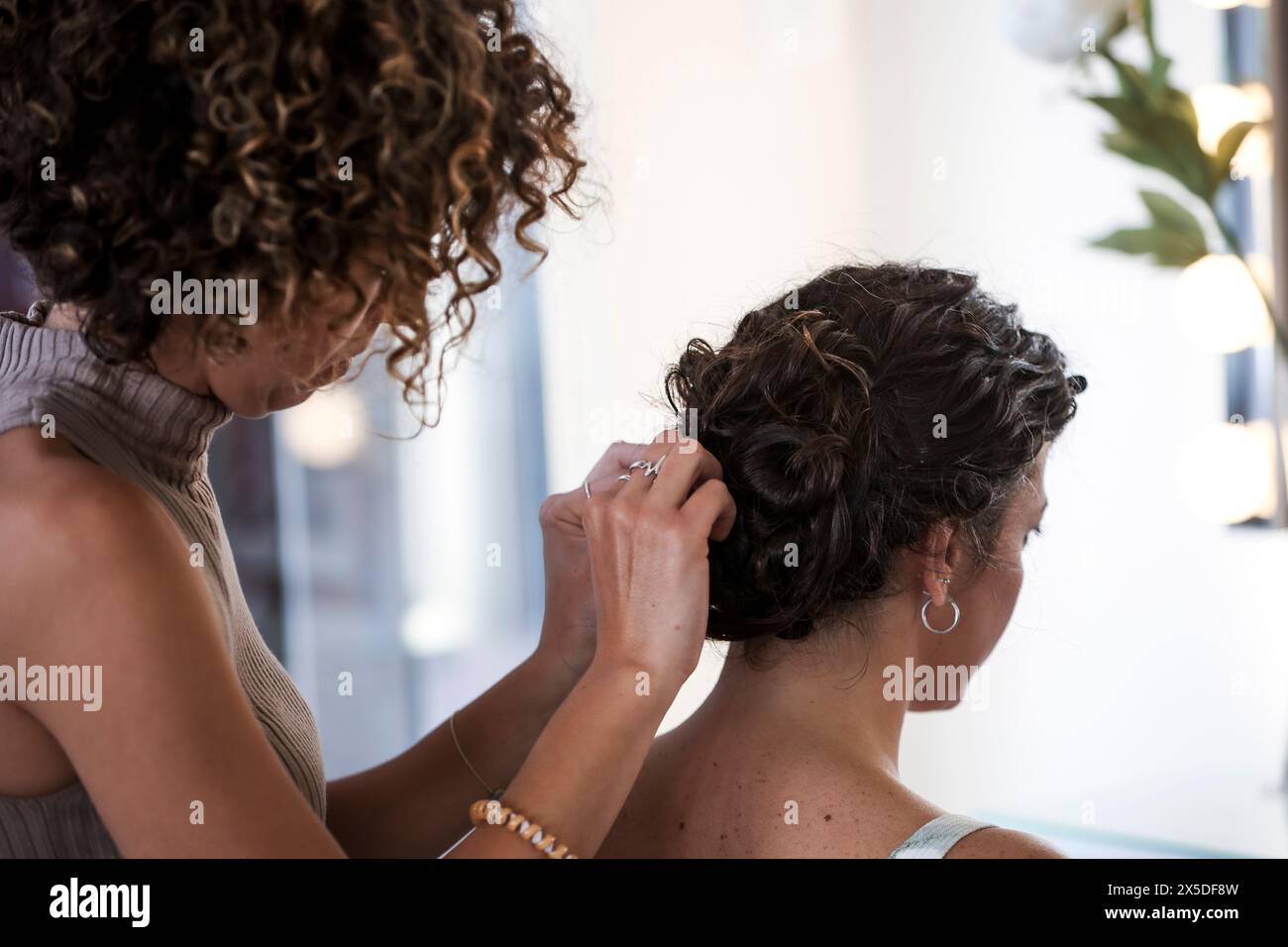 Styliste professionnel travaillant avec le client de cheveux bouclés Banque D'Images